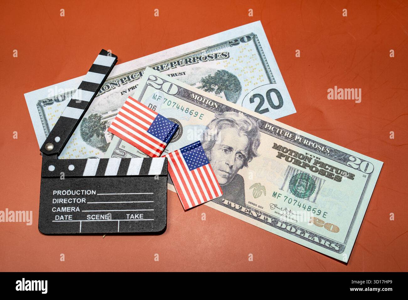 Un tabellone di clapper cinematografico si trova accanto alla valuta americana e alle piccole bandiere, suggerendo la finanza cinematografica e la realizzazione di film patriottici. Foto Stock