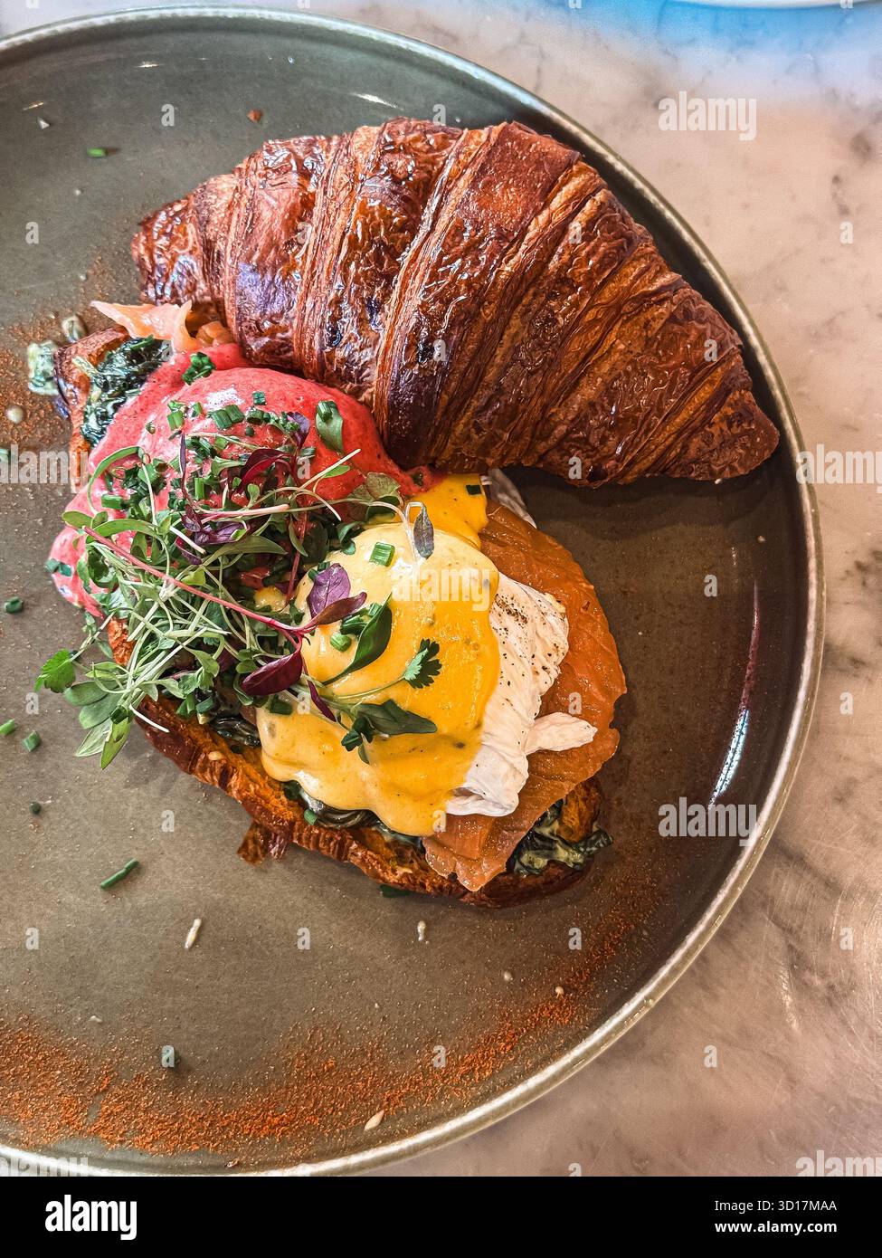 Croissant francese con salmone affumicato, uovo in camicia e salsa hollandaise Foto Stock
