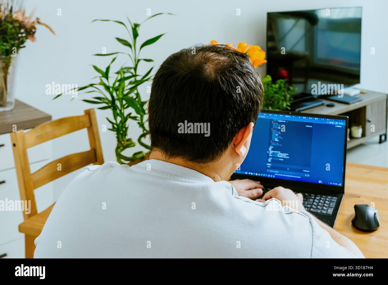 Un uomo siede su un notebook e utilizza l'intelligenza artificiale, vista da dietro. Foto di alta qualità Foto Stock