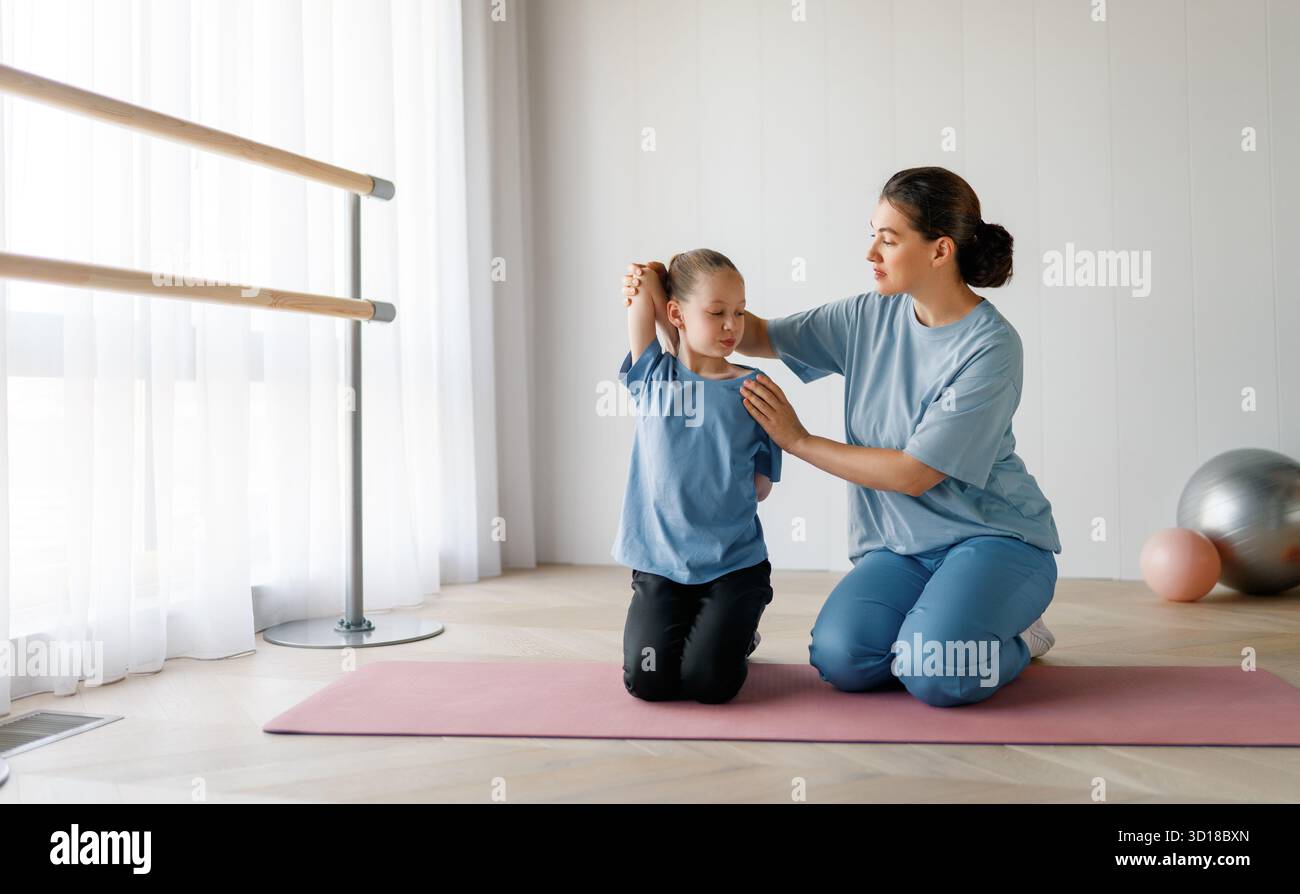 Il bambino sta subendo una terapia fisica. La ragazza sta facendo esercizi sotto la supervisione del medico. Foto Stock