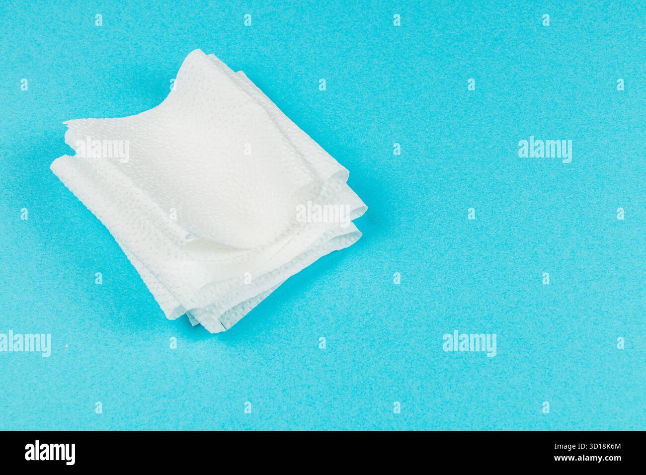 Le salviette bianche soffici sono impilate con cura su uno sfondo blu brillante, che ne mostra la disposizione e la consistenza. Ideale per varie attività di pulizia. Foto Stock