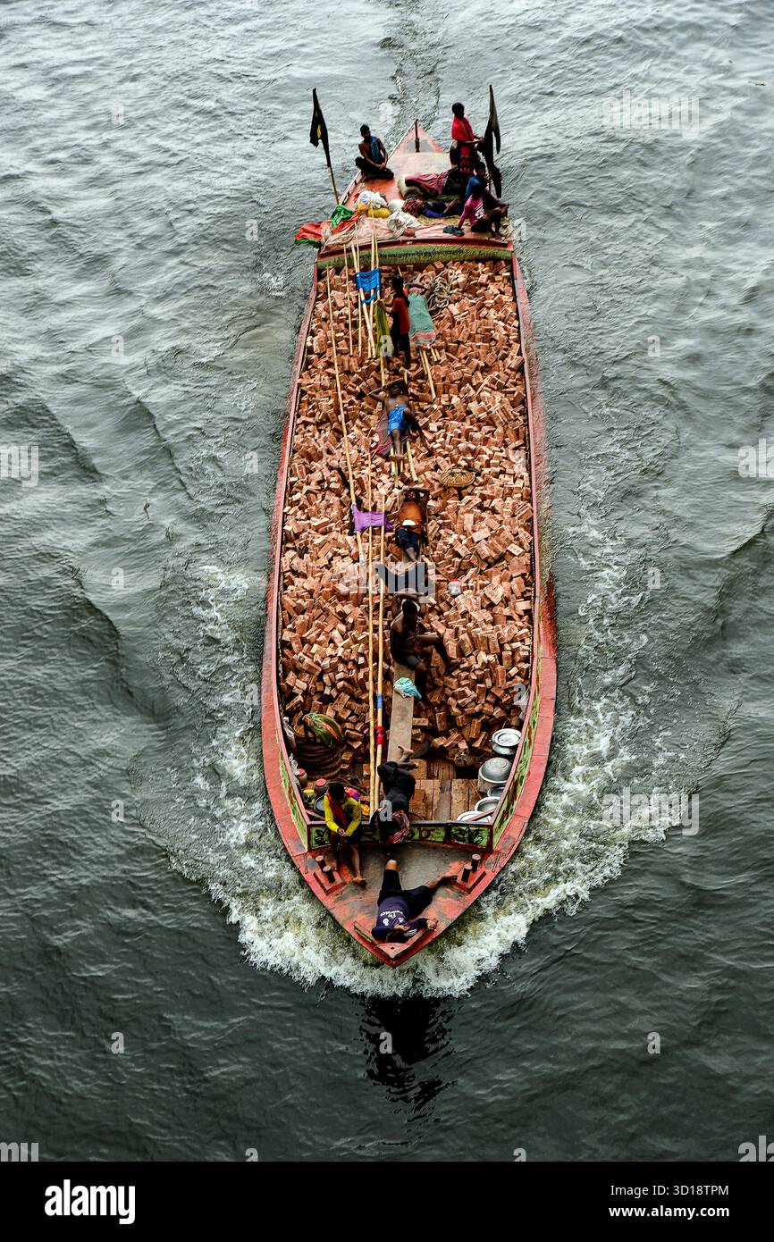 Vista aerea della barca che trasporta mattoni sulle acque calme con i lavoratori Foto Stock