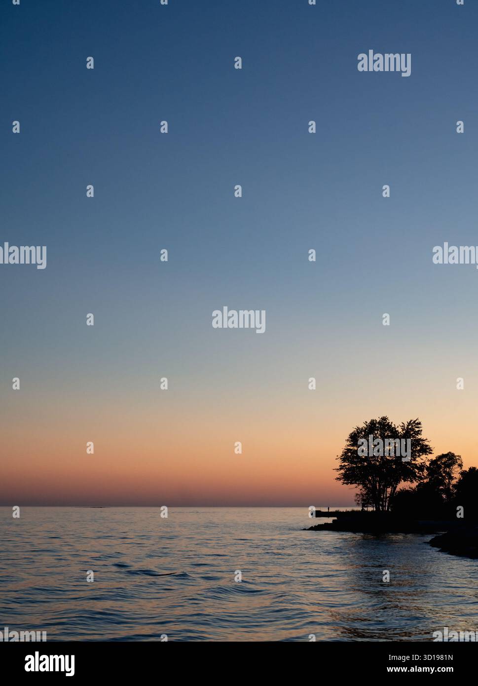 Luce arancione del tramonto sull'acqua dalla riva del lago Ontario. Foto Stock