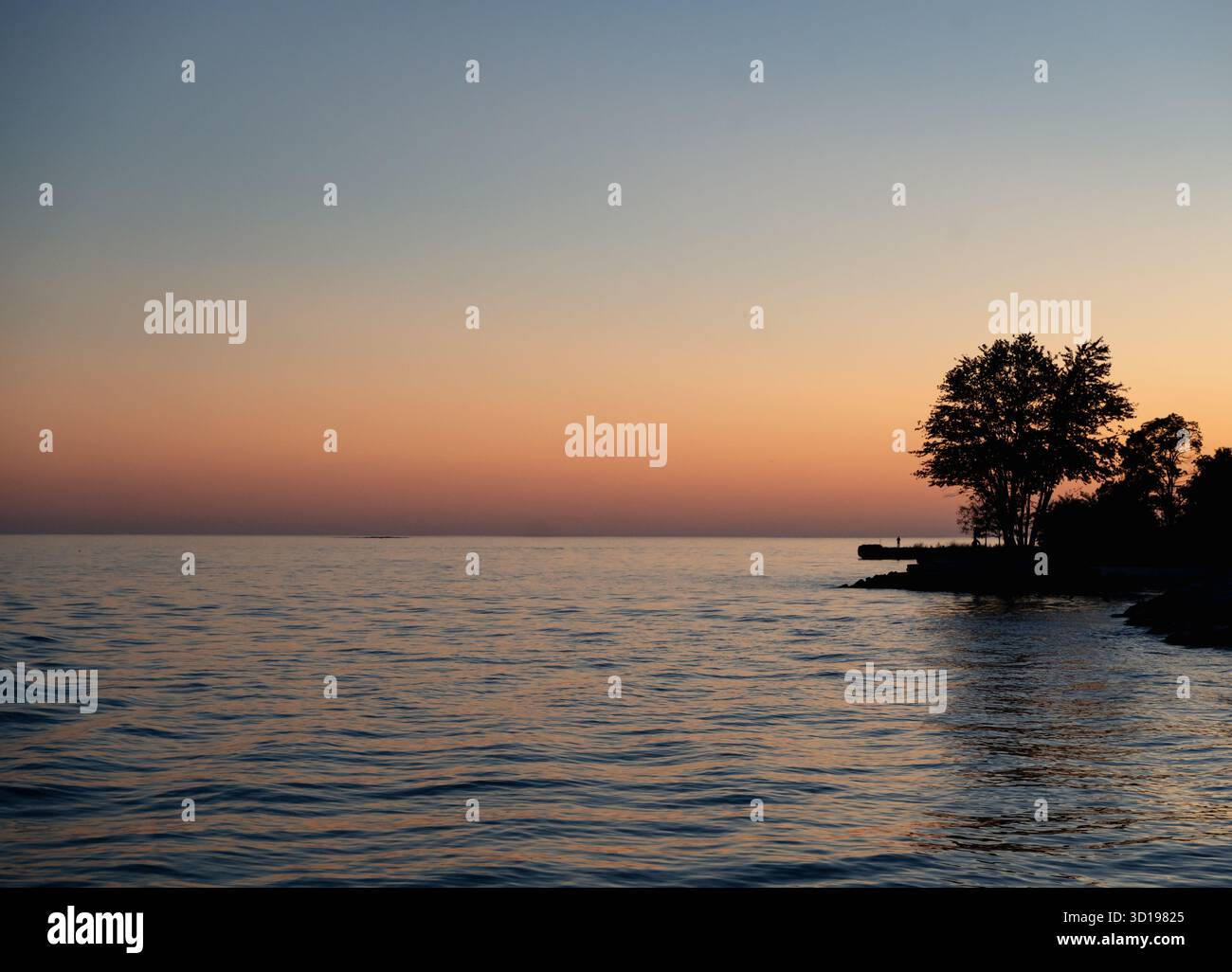 Luce arancione del tramonto sull'acqua dalla riva del lago Ontario. Foto Stock