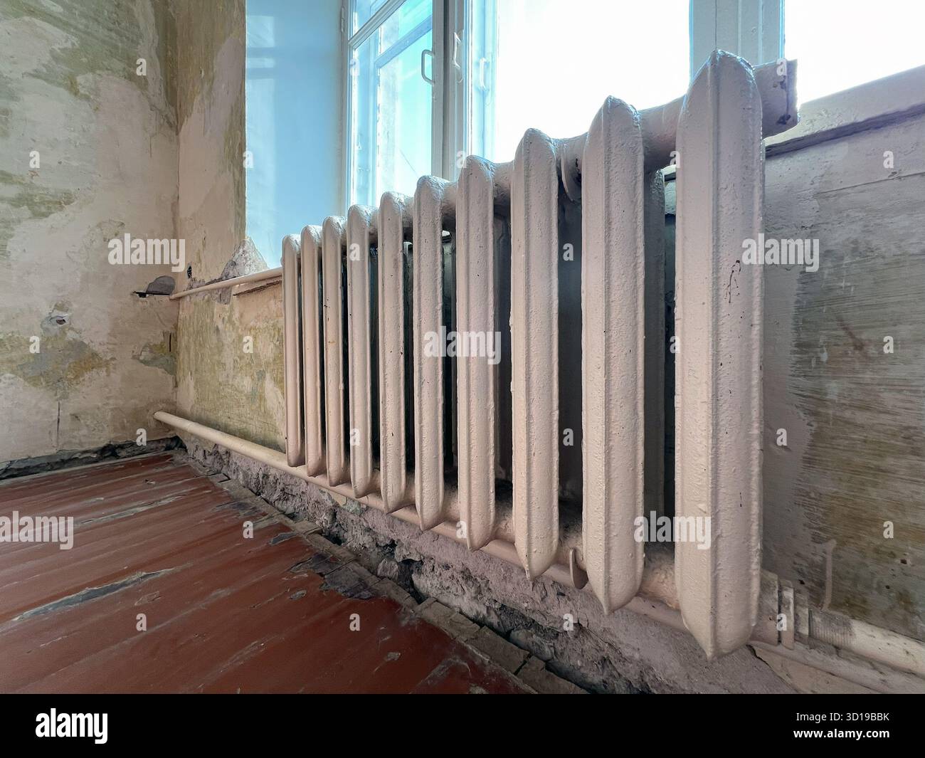 La vecchia batteria di riscaldamento in ghisa vicino alla finestra della camera è in fase di ristrutturazione Foto Stock