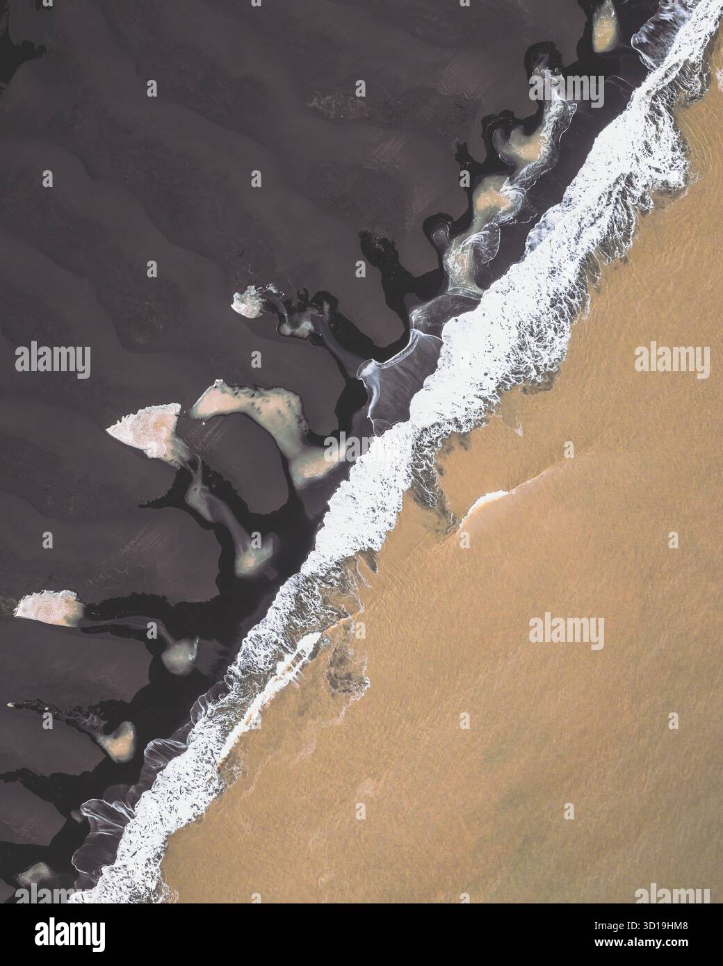 Veduta aerea del forte contrasto tra la sabbia nera e le onde bianche spumeggianti che incontrano la costa dorata di Kvíárjökull, Sveitarfélagið Hornafjörður, Islanda. Foto Stock