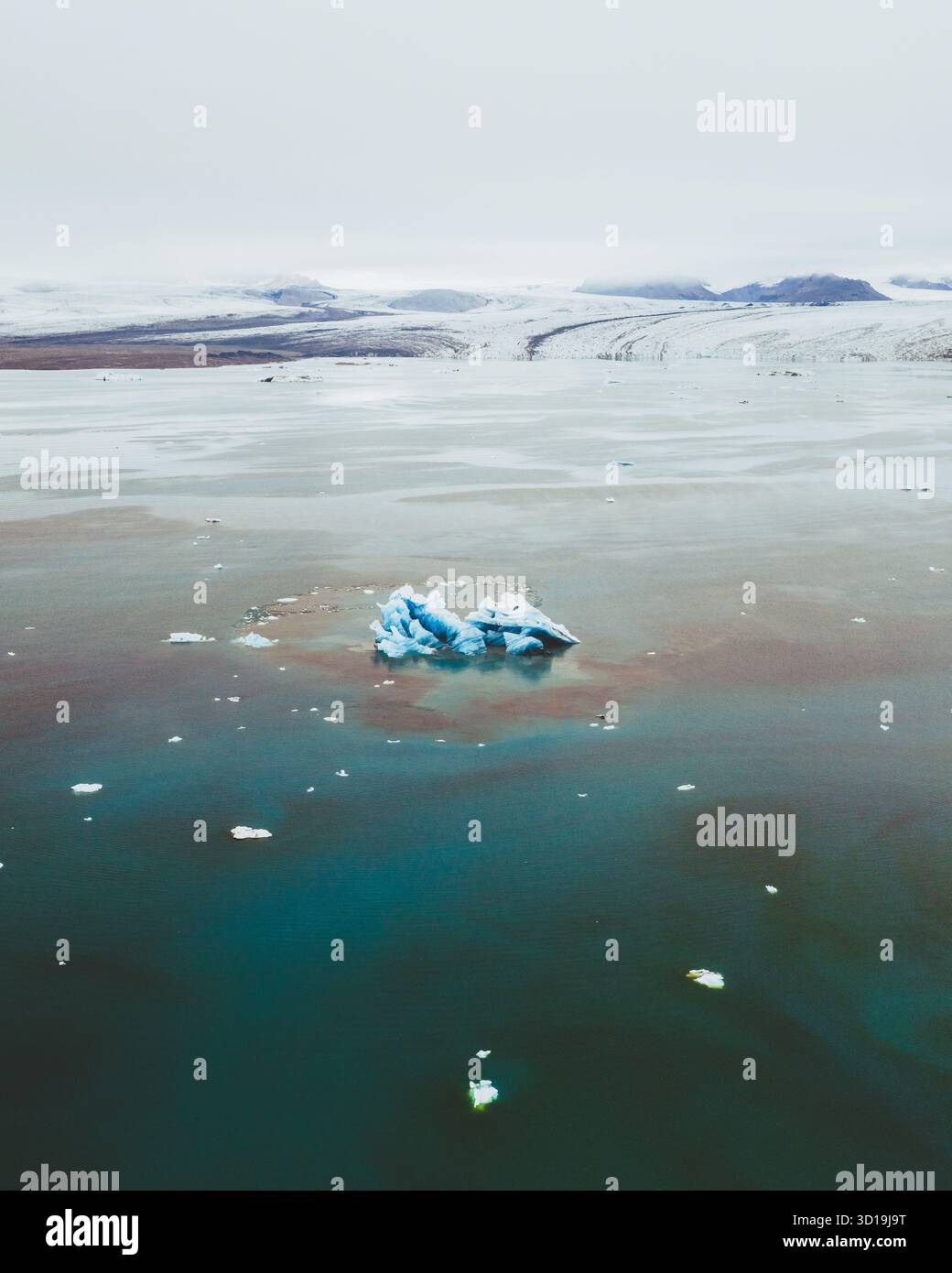 Vista aerea degli iceberg glaciali che riflettono le sfumature pallide del cielo tra le serene e scure acque di Jökulsárlón, Sveitarfélagið Hornafjörður, Islanda. Foto Stock