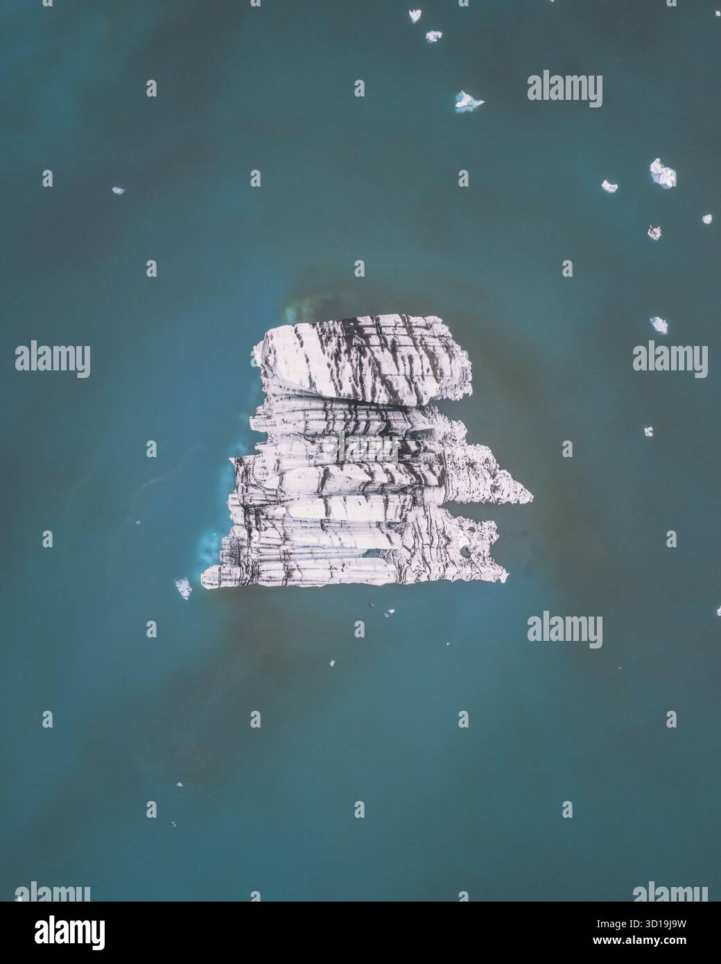 Vista aerea di un colossale iceberg, scolpito dal tempo, galleggia serenamente sulle tranquille acque turchesi di Jökulsárlón, Sveitarfélagið Hornafjörður, Islanda. Foto Stock