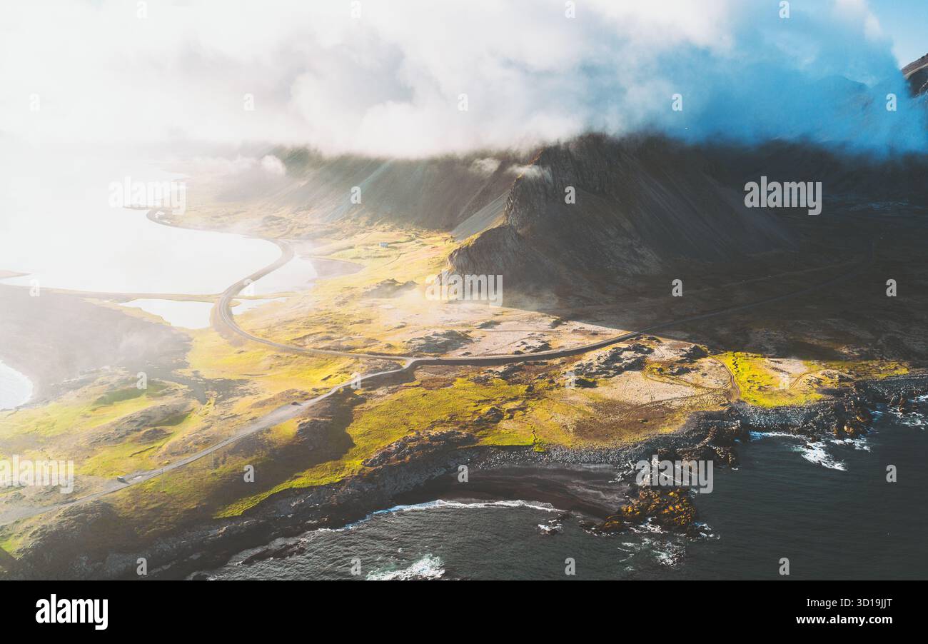 Vista aerea delle strade tortuose che tracciano la costa frastagliata sotto un velo di montagne baciate dalla nebbia, Hvalnesviti, Sveitarfélagið Hornafjörður, Islanda. Foto Stock