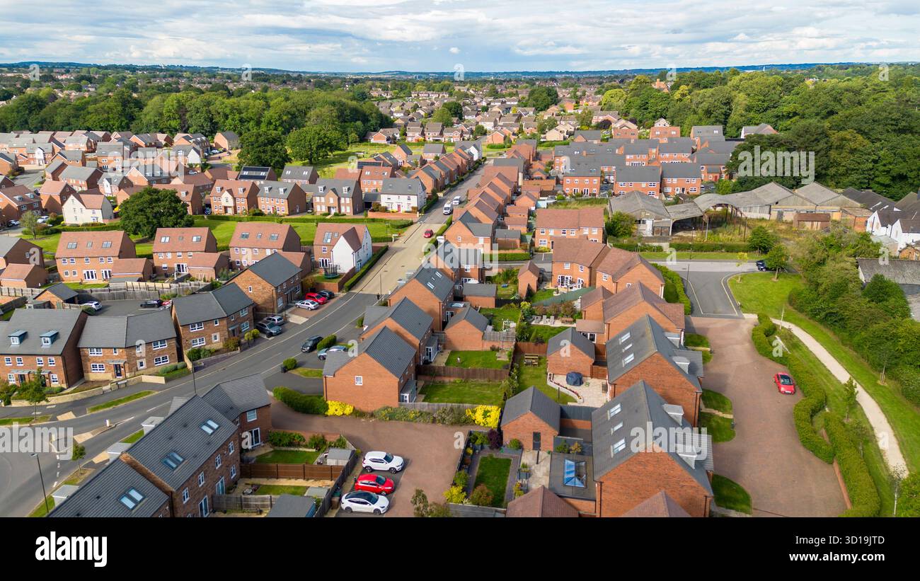 Foto aerea del drone sopra Cotchett Village, Mickleover, Derby, mostrando file ordinate di moderne case in mattoni e spazi verdi. Foto Stock