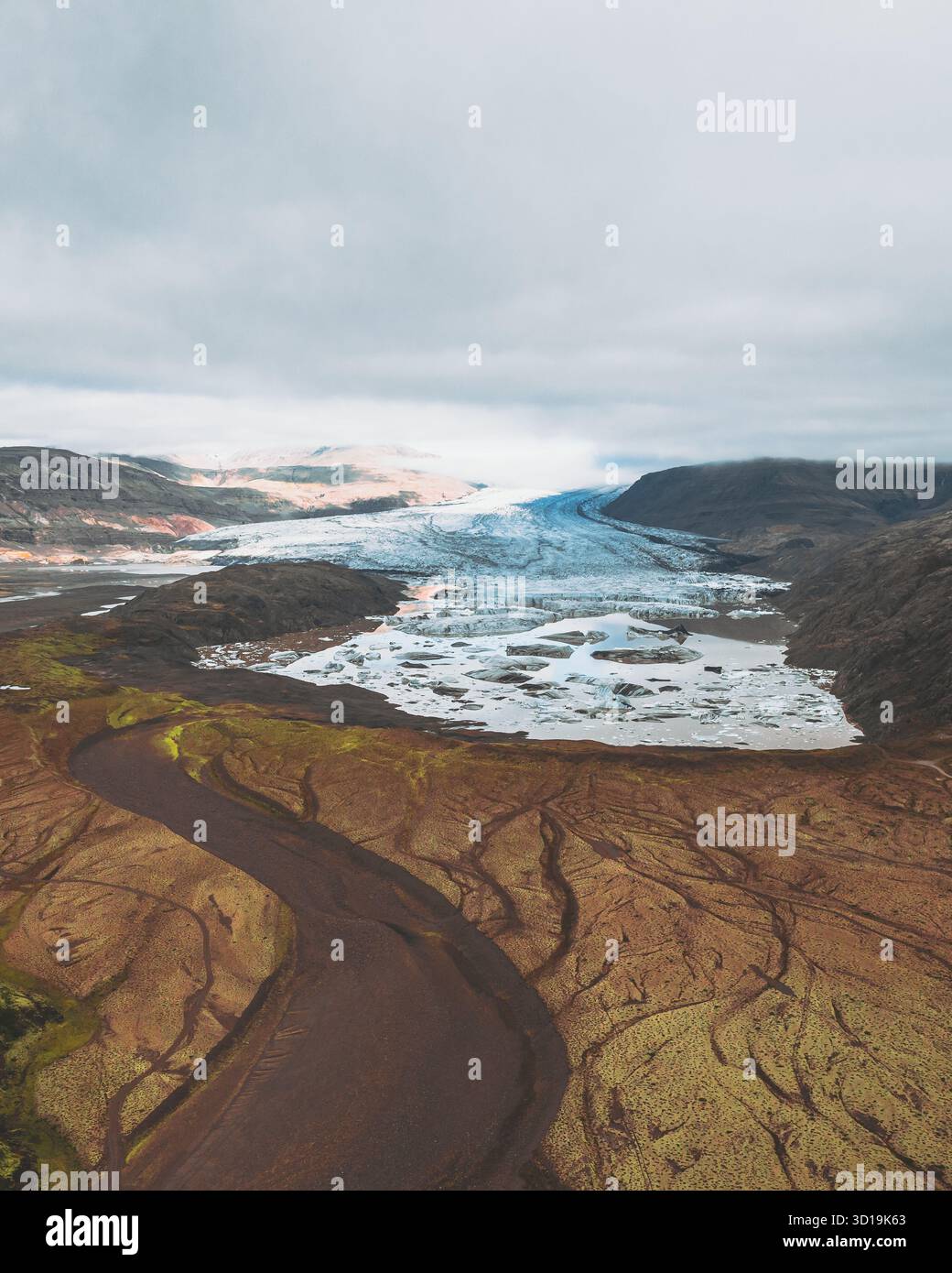 Vista aerea dei ghiacciai blu ghiacciati incontra il terreno aspro e terroso sotto un cielo nuvoloso, Heinabergsjökull, Sveitarfélagið Hornafjörður, Islanda. Foto Stock