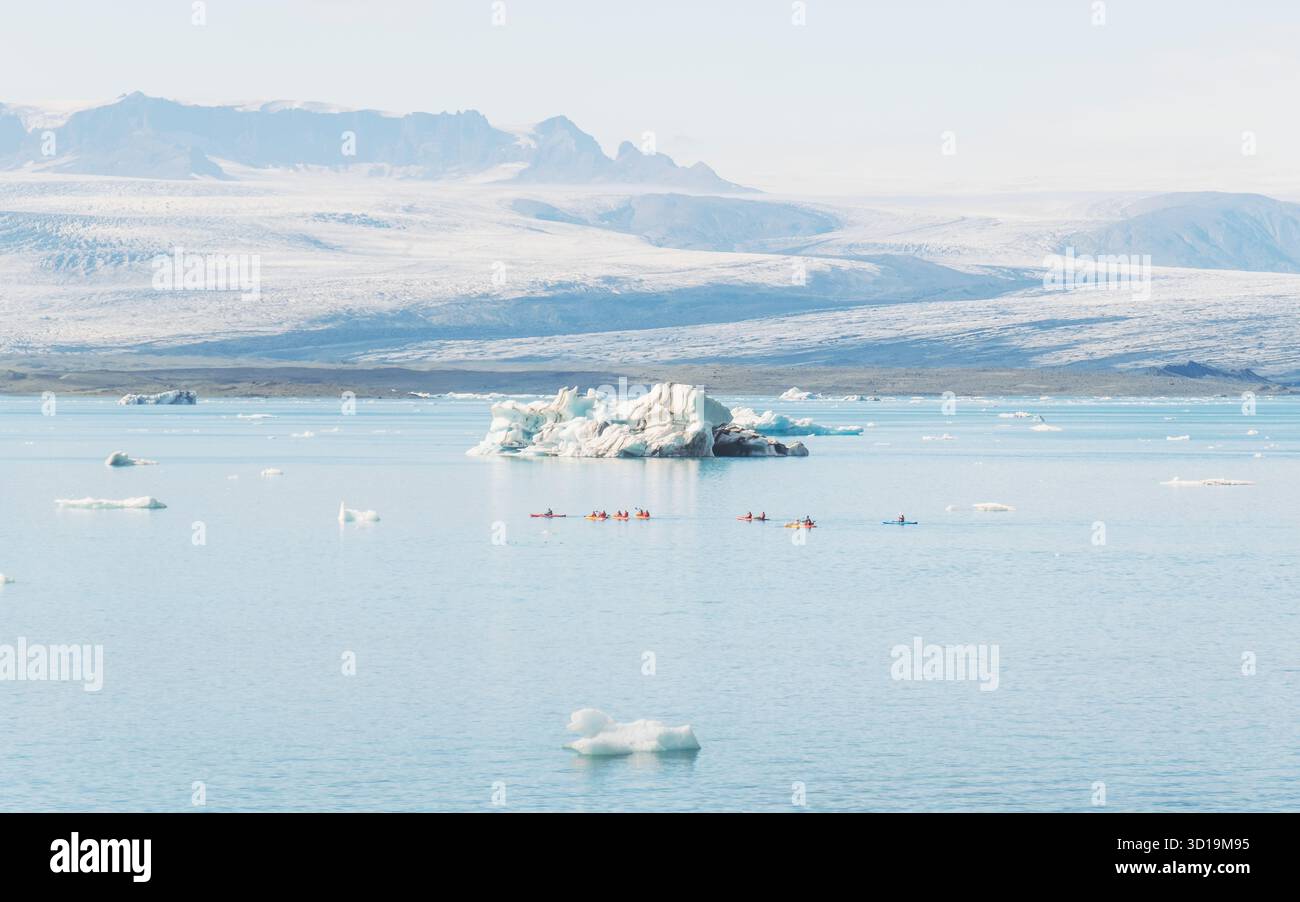 Vista degli iceberg alla deriva della laguna glaciale, i loro bianchi ghiacciati contrastano con il blu profondo e un ghiacciaio lontano, Jökulsárlón, Sveitarfélagið Hornafjörður, Islanda. Foto Stock