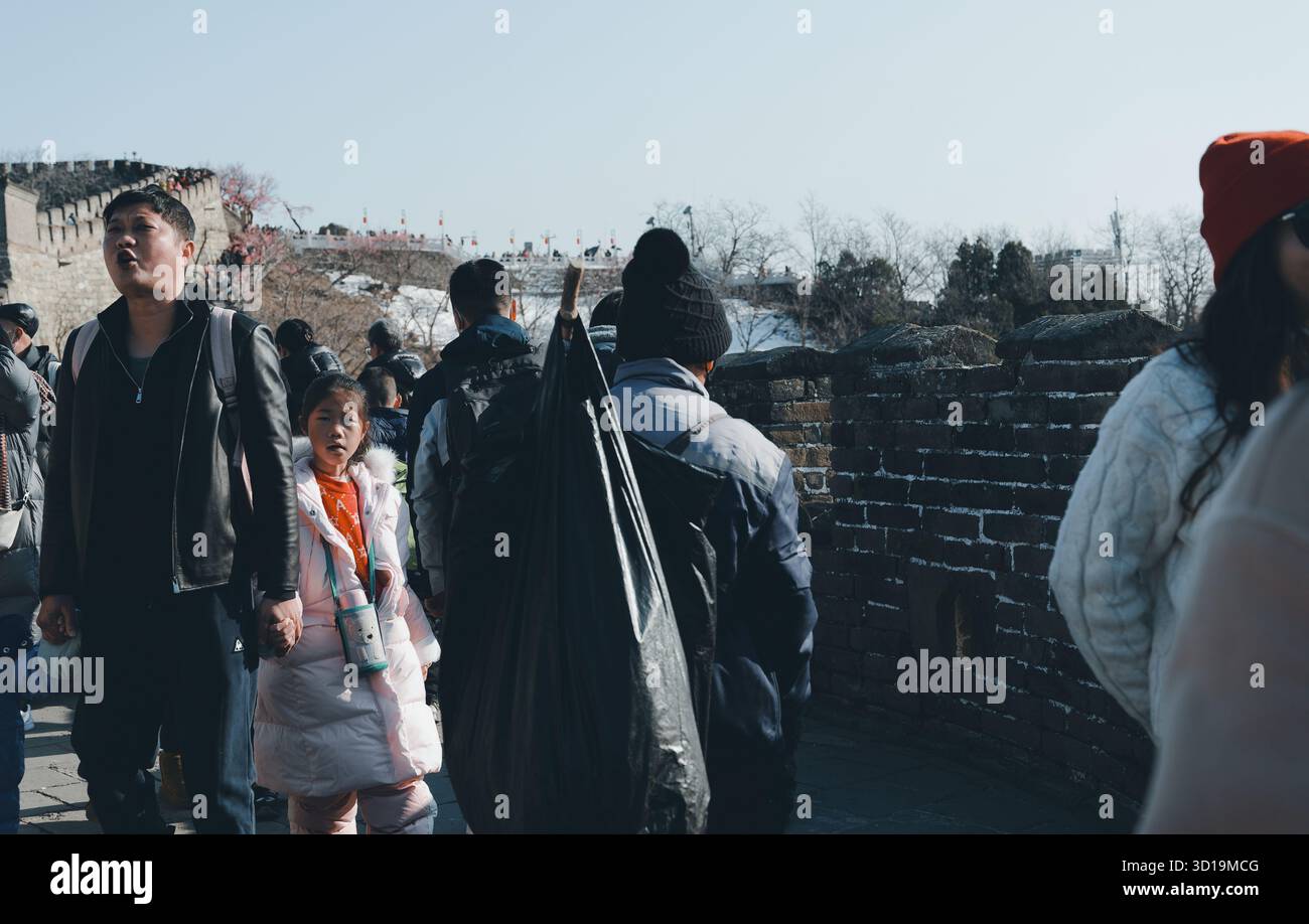 Un operatore sanitario trasporta grandi sacchi di immondizia lungo la grande Muraglia Cinese Foto Stock