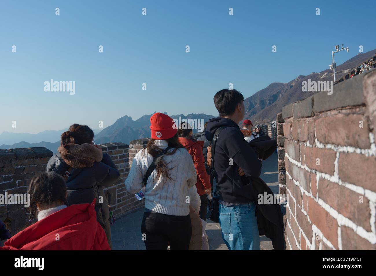 I visitatori camminano lungo la grande Muraglia Cinese sotto il cielo azzurro Foto Stock