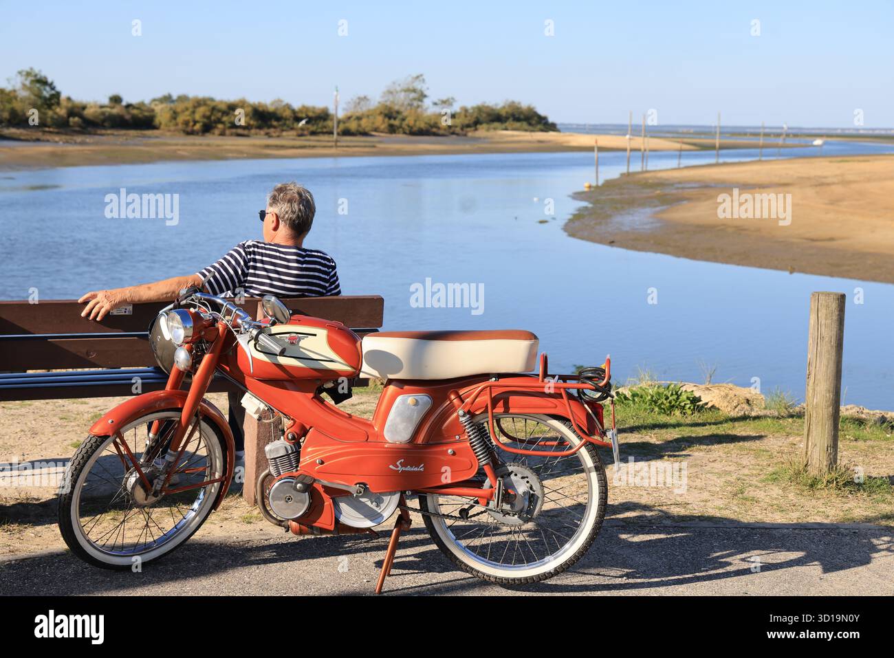 Calma e bellezza del bacino di Arcachon: Uomo con un ciclomotore d'epoca che contempla la baia di Arcachon. Francia Foto Stock