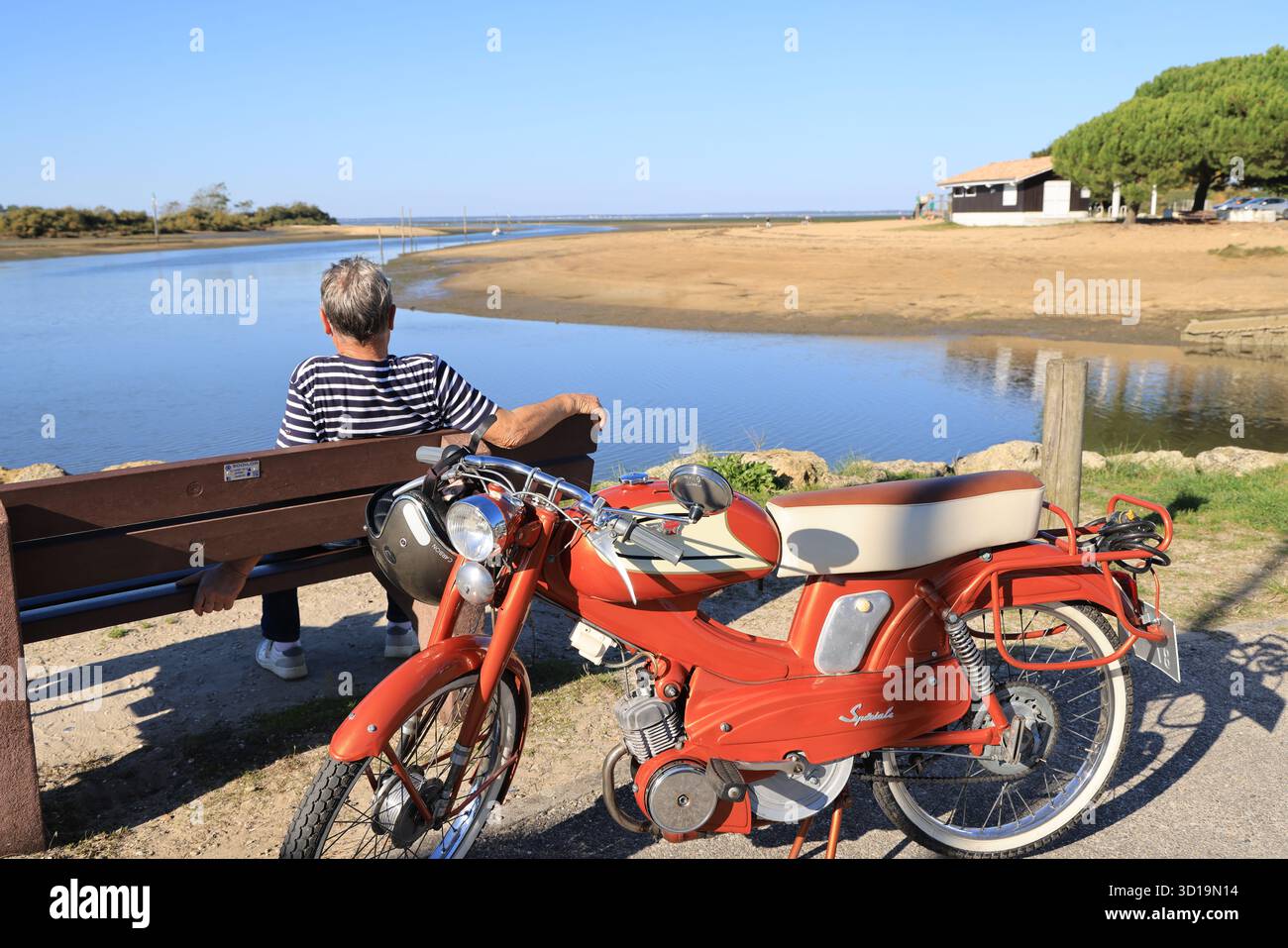 Calma e bellezza del bacino di Arcachon: Uomo con un ciclomotore d'epoca che contempla la baia di Arcachon. Francia Foto Stock