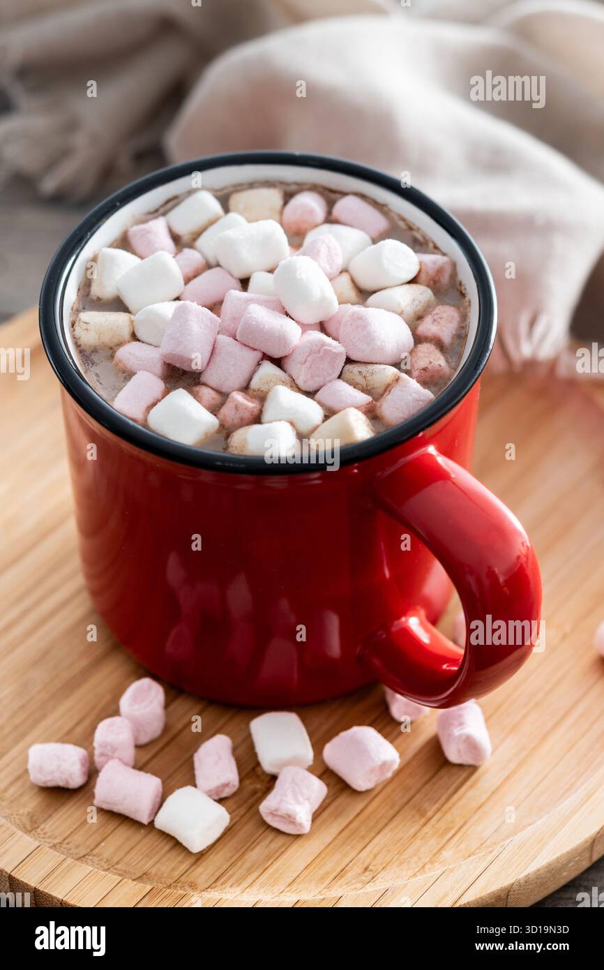 Bevanda calda a base di cioccolata con marshmallow in tazza rossa su un tavolo di legno Foto Stock