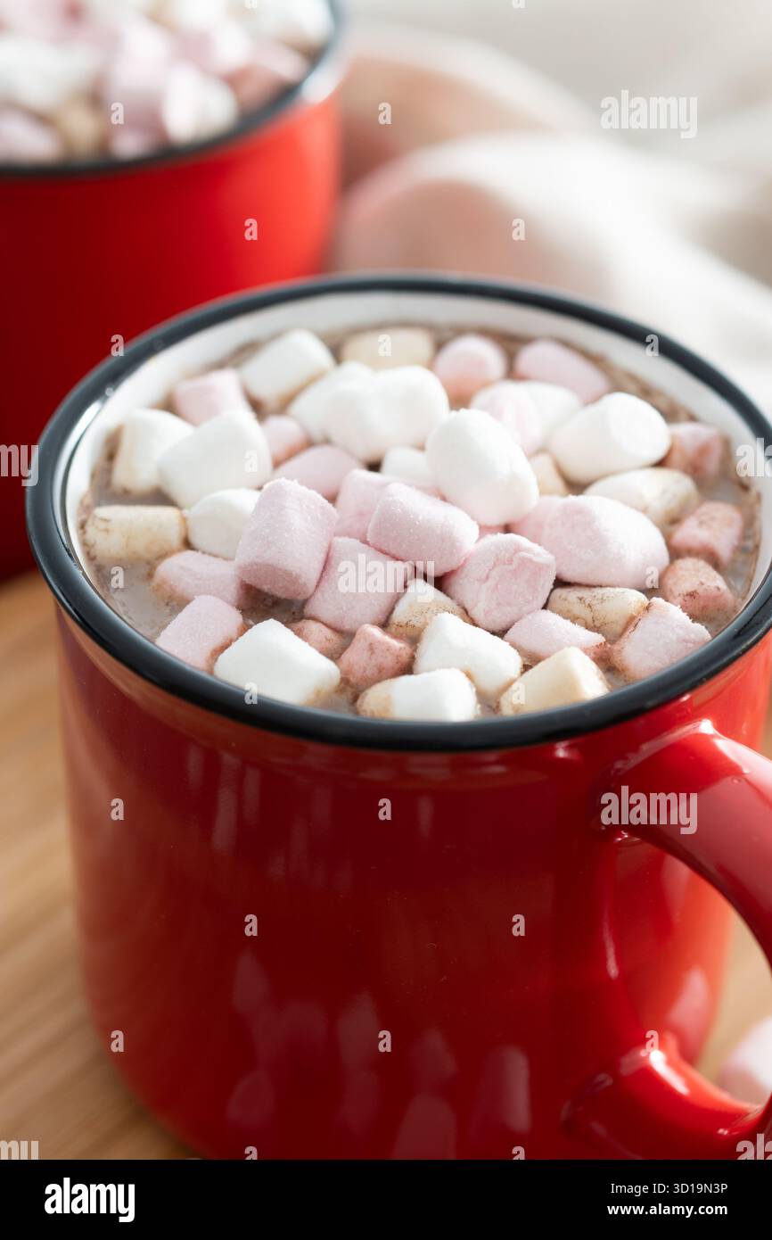 Bevanda calda a base di cioccolata con marshmallow in tazza rossa su un tavolo di legno Foto Stock