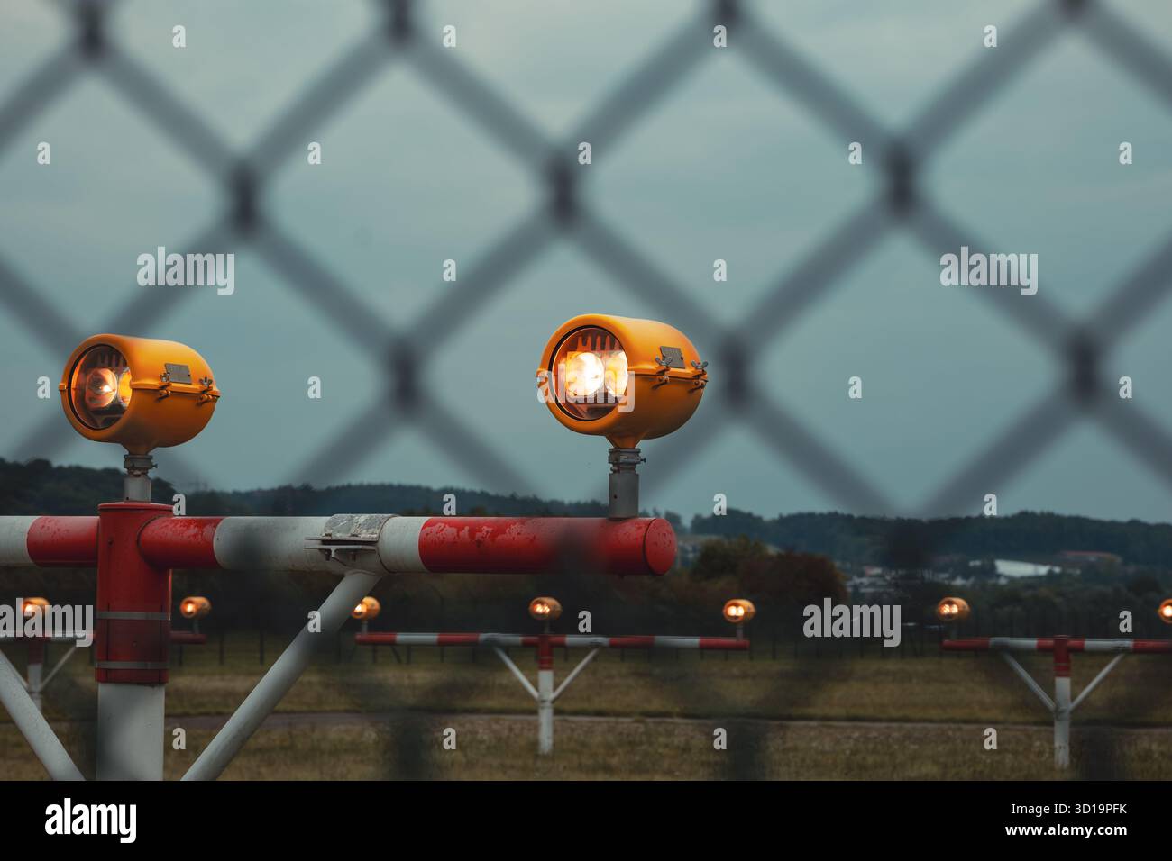 L'indicatore del percorso di avvicinamento di precisione si illumina di fronte a una pista aeroportuale vuota e alle luci laterali. Primo piano dei gruppi di luce, buio, moody, Foto Stock