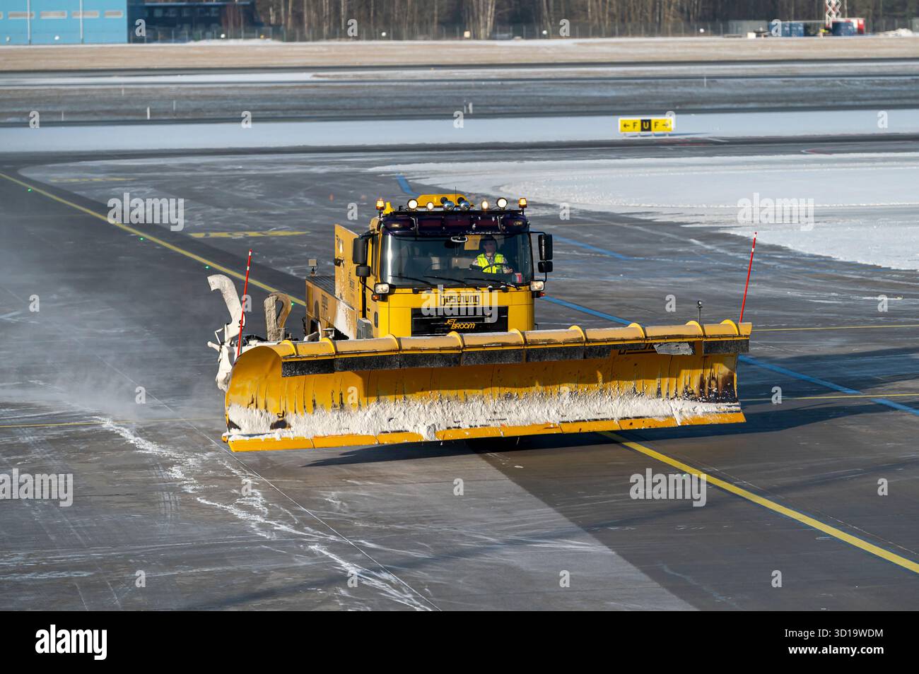 Riga, Lettonia - 15 febbraio 2025: Un veicolo specializzato sgombra la neve dalla pista dell'aeroporto di riga in inverno. Foto Stock