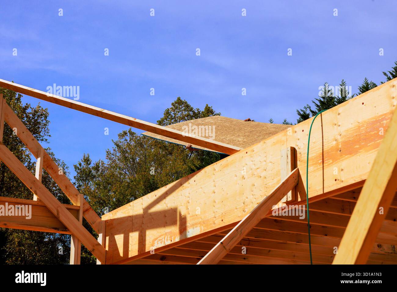 Gli operai edili installano materiali per tetti su travi in legno nel quartiere periferico Foto Stock