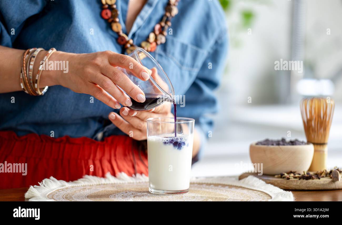 La donna versa Un Matcha latte con ghiaccio e latte in Un barattolo Foto Stock