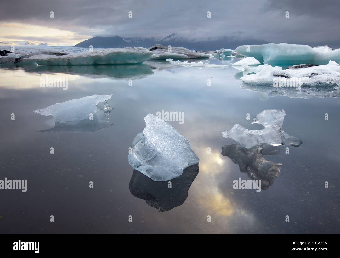 La vista degli scintillanti iceberg si snoda serenamente attraverso la laguna glaciale, riflettendo il cielo lunare e le montagne lontane, Jokulsarlon, Sveitarfélagið Hornafjörður, Islanda. Foto Stock