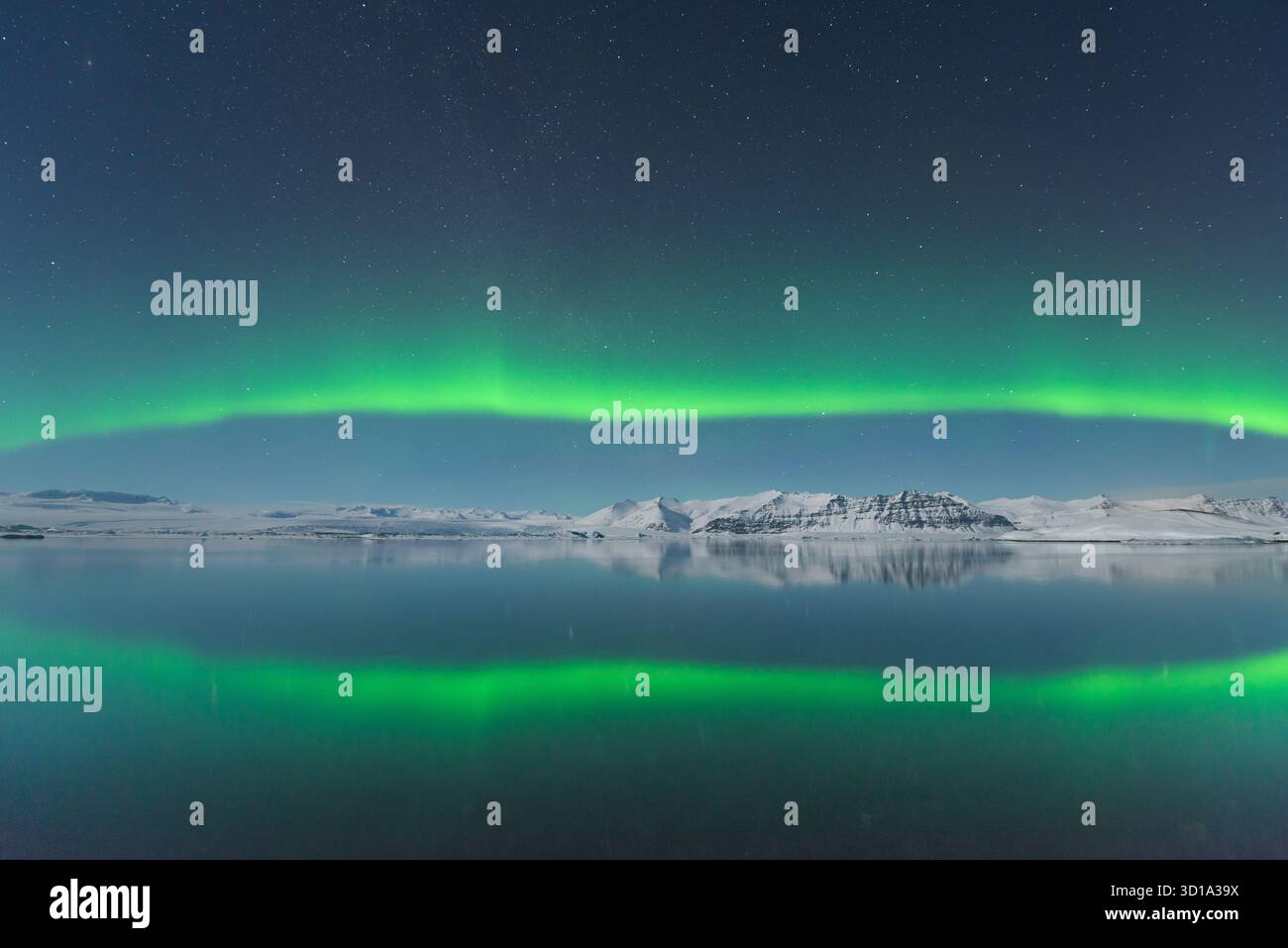La vista dell'eterea aurora boreale verde dona sopra le serene acque riflettenti, che rispecchiano lo spettacolo celeste, Jokulsarlon, Sveitarfélagið Hornafjörður, Islanda. Foto Stock