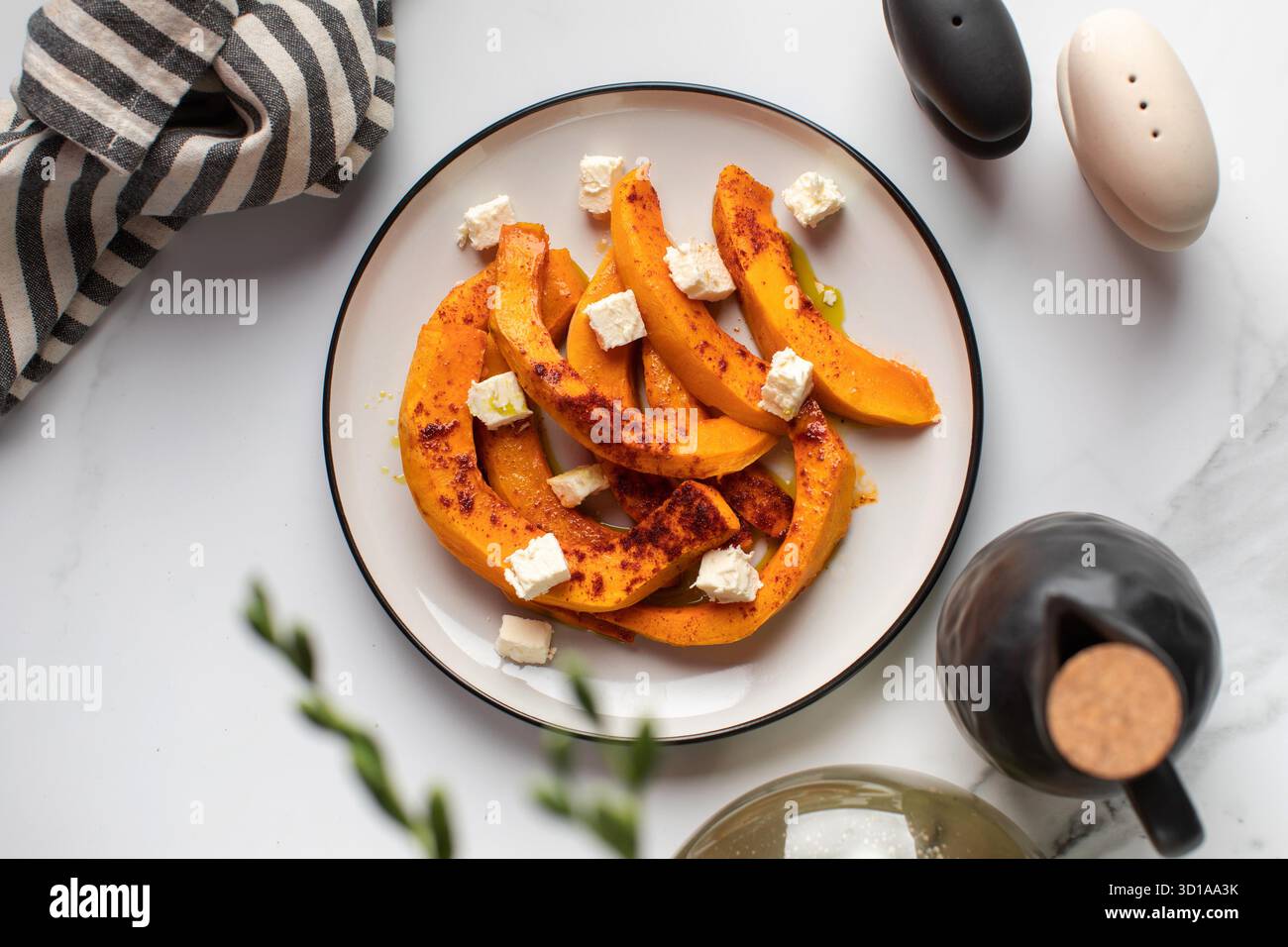 Fette di zucca al forno con spezie e cubetti di feta. Ricette autunnali, piatti di zucca. Foto Stock