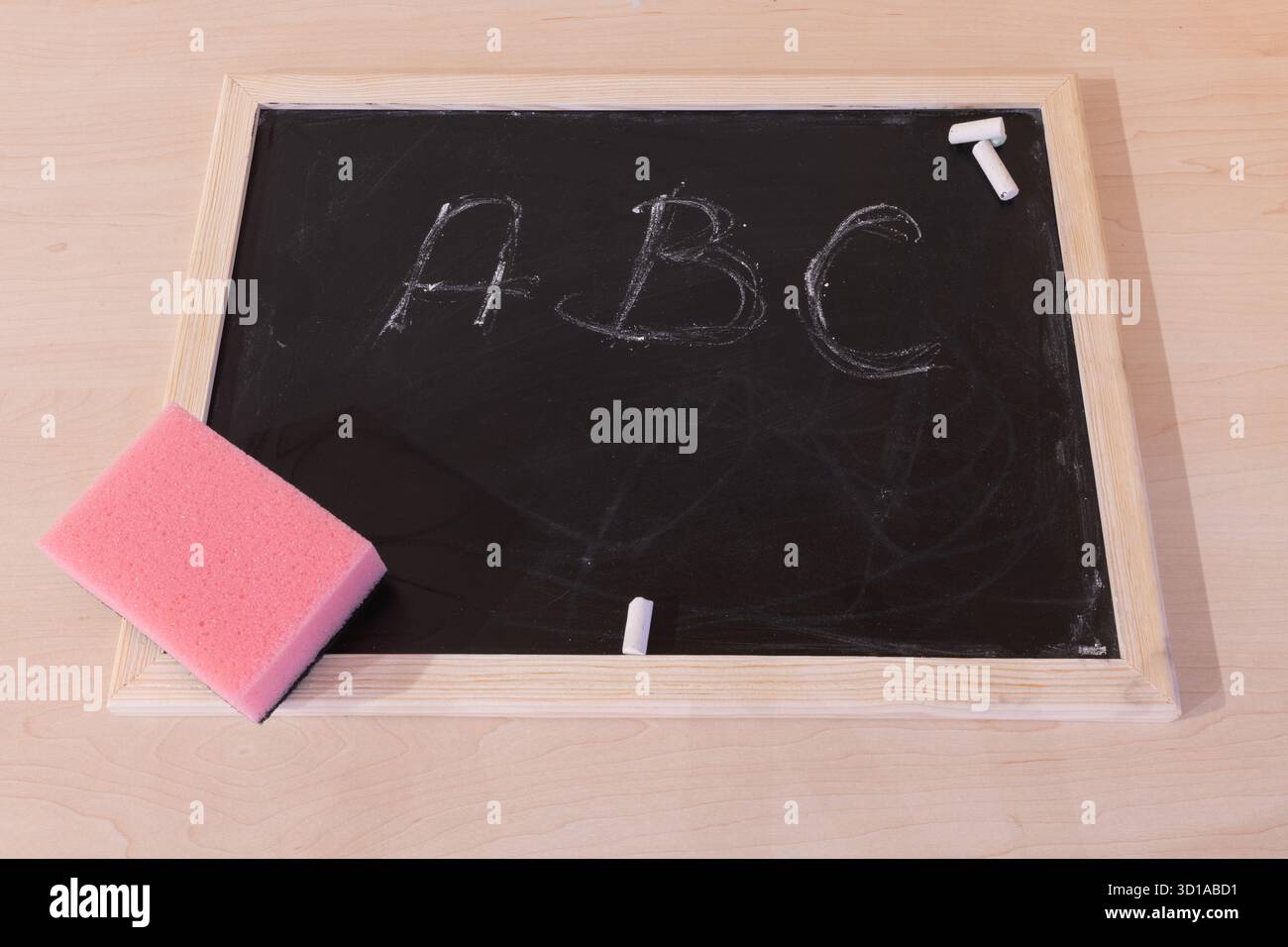 Vista dall'alto della lavagna con spugna rosa e gesso bianco. Sulla lavagna ha scritto lettere B C. Foto Stock