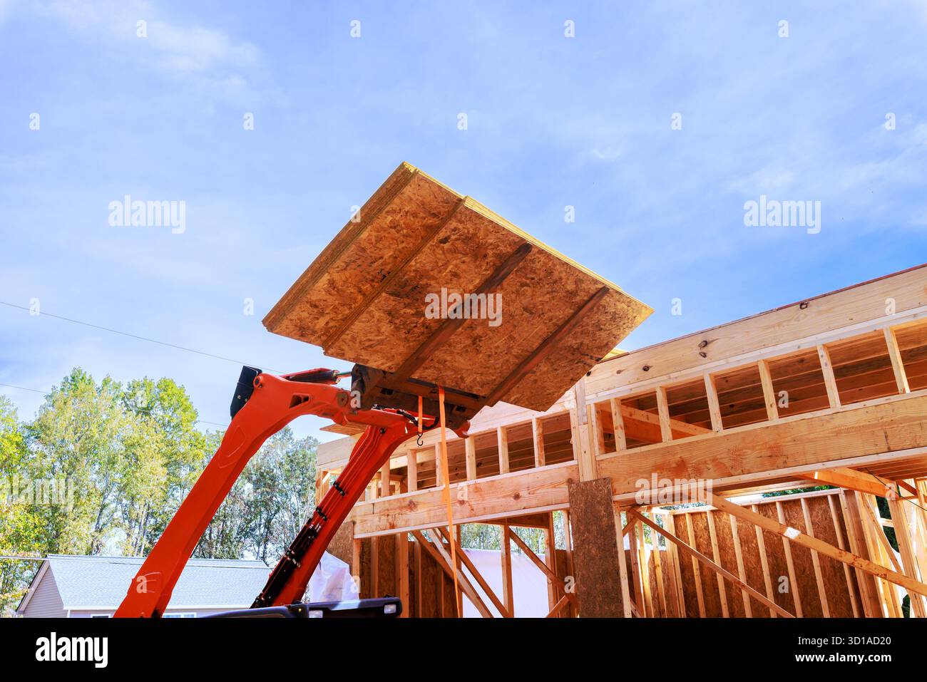 Il carrello solleva la tavola osb in legno per completare l'inquadratura della casa sotto il quartiere periferico. Foto Stock