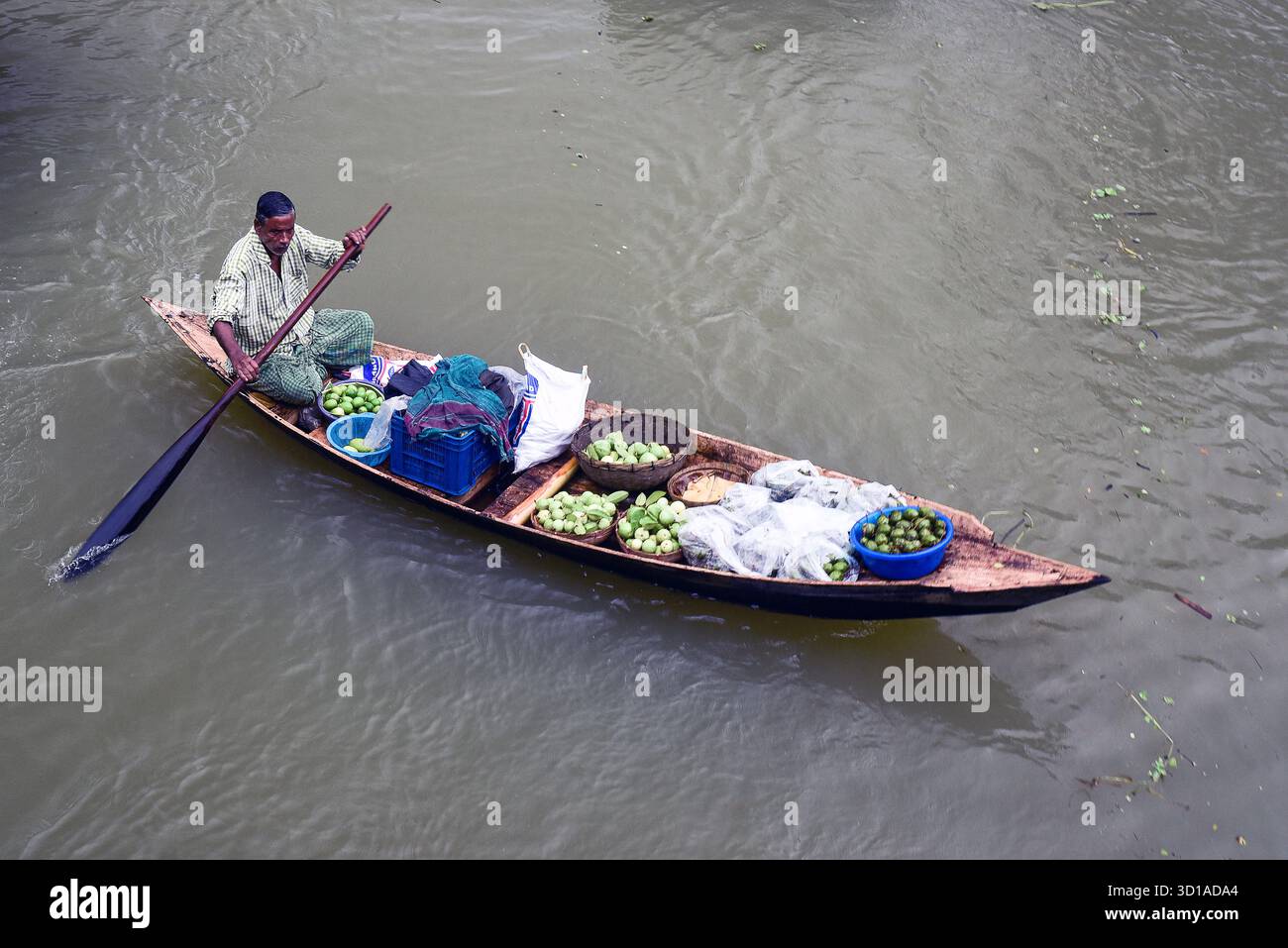 River Merchant che vendono frutta fresca da una barca di legno sull'acqua torbida durante il giorno del mercato Foto Stock