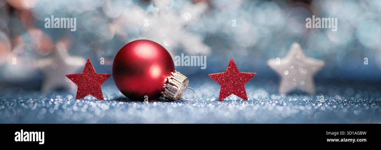Ornamenti natalizi rossi e bianchi su sfondo blu sfocato e superficie scintillante Foto Stock