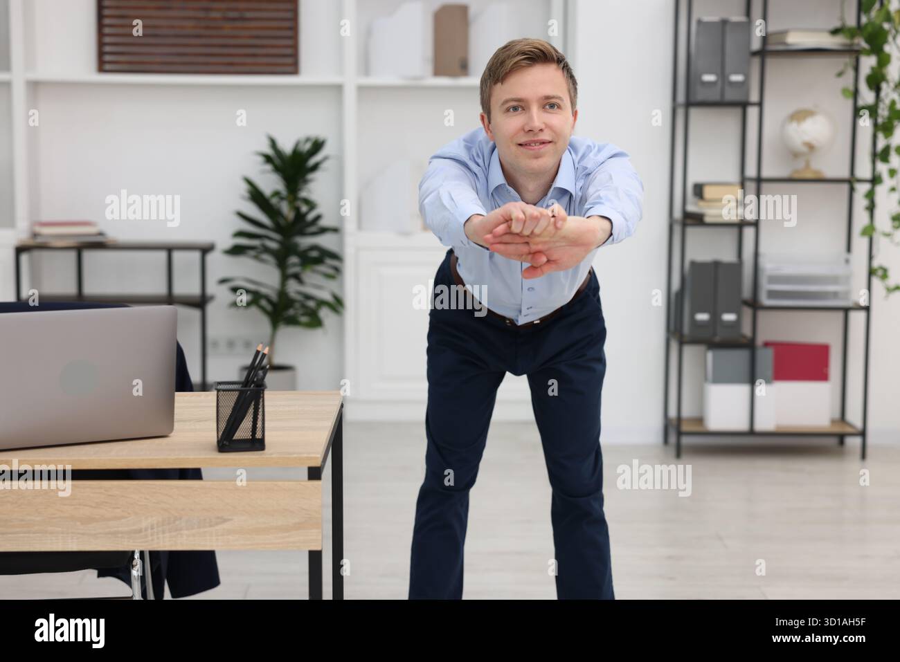 Giovane uomo d'affari che fa esercizio di stretching in ufficio Foto Stock