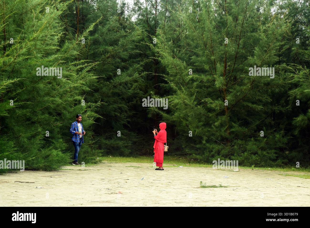 Due persone in Una radura della foresta verde, una donna in rosso che fa foto insieme Foto Stock