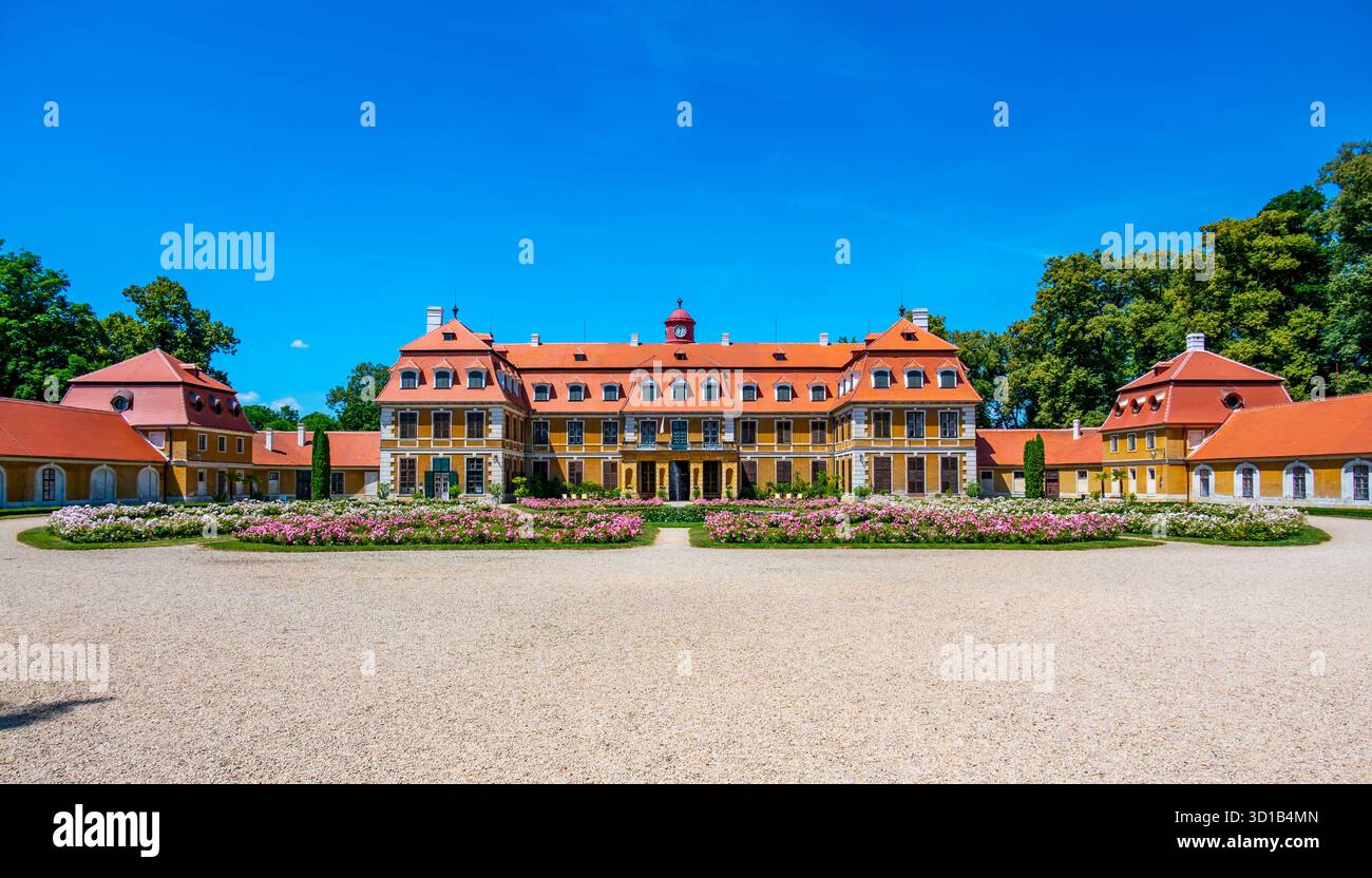 Vista panoramica del castello di Rajec Jestrebi in una soleggiata giornata estiva con cielo blu, rose rosa fiorenti e una fontana di fronte all'edificio storico. Foto Stock