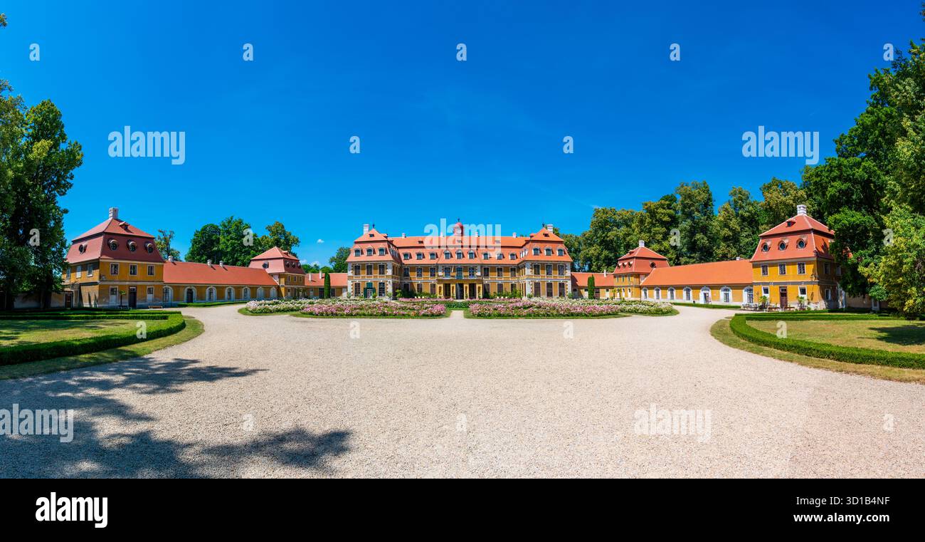 Vista panoramica del castello di Rajec Jestrebi in una soleggiata giornata estiva con cielo blu, rose rosa fiorenti e una fontana di fronte all'edificio storico. Foto Stock