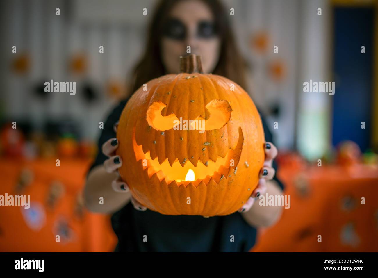 Le mani della ragazza tengono in mano una divertente zucca bianca di Halloween con uno sfondo nero sfocato Foto Stock