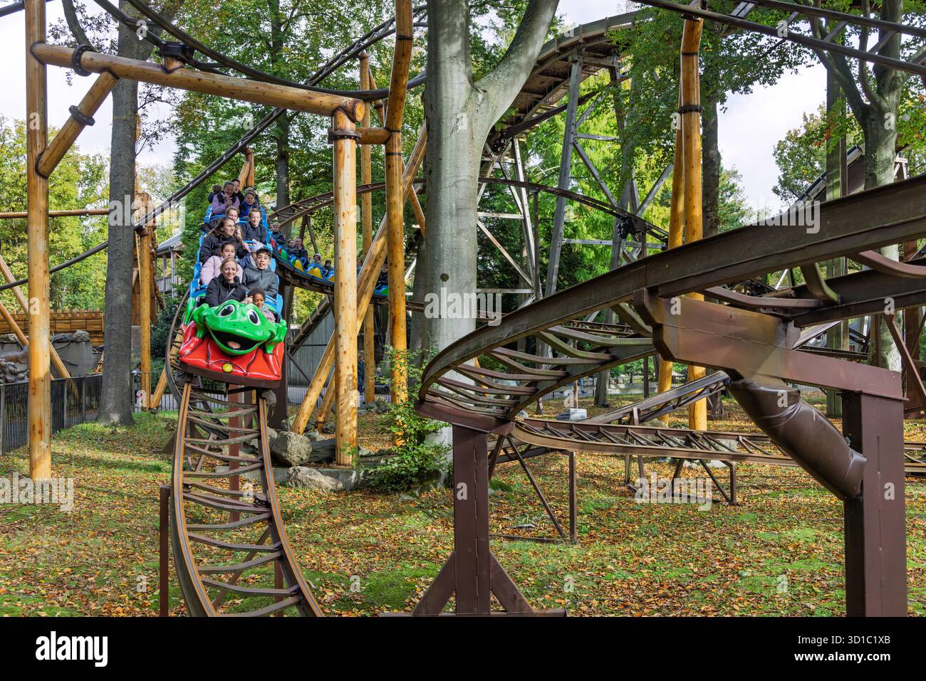 Una vivace carrozza a tema rana verde a Duinrell attraversa un'area boscosa con ciclisti entusiasti che si divertono per tutta la famiglia. Wassena Foto Stock