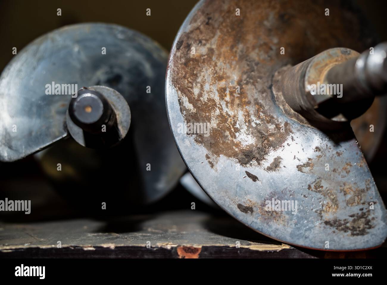 Primo piano delle teste di perforazione metalliche usurate che mostrano la struttura della lama a spirale, la ruggine e l'usura meccanica utilizzate nella perforazione del terreno e nei lavori di costruzione di fondazioni Foto Stock
