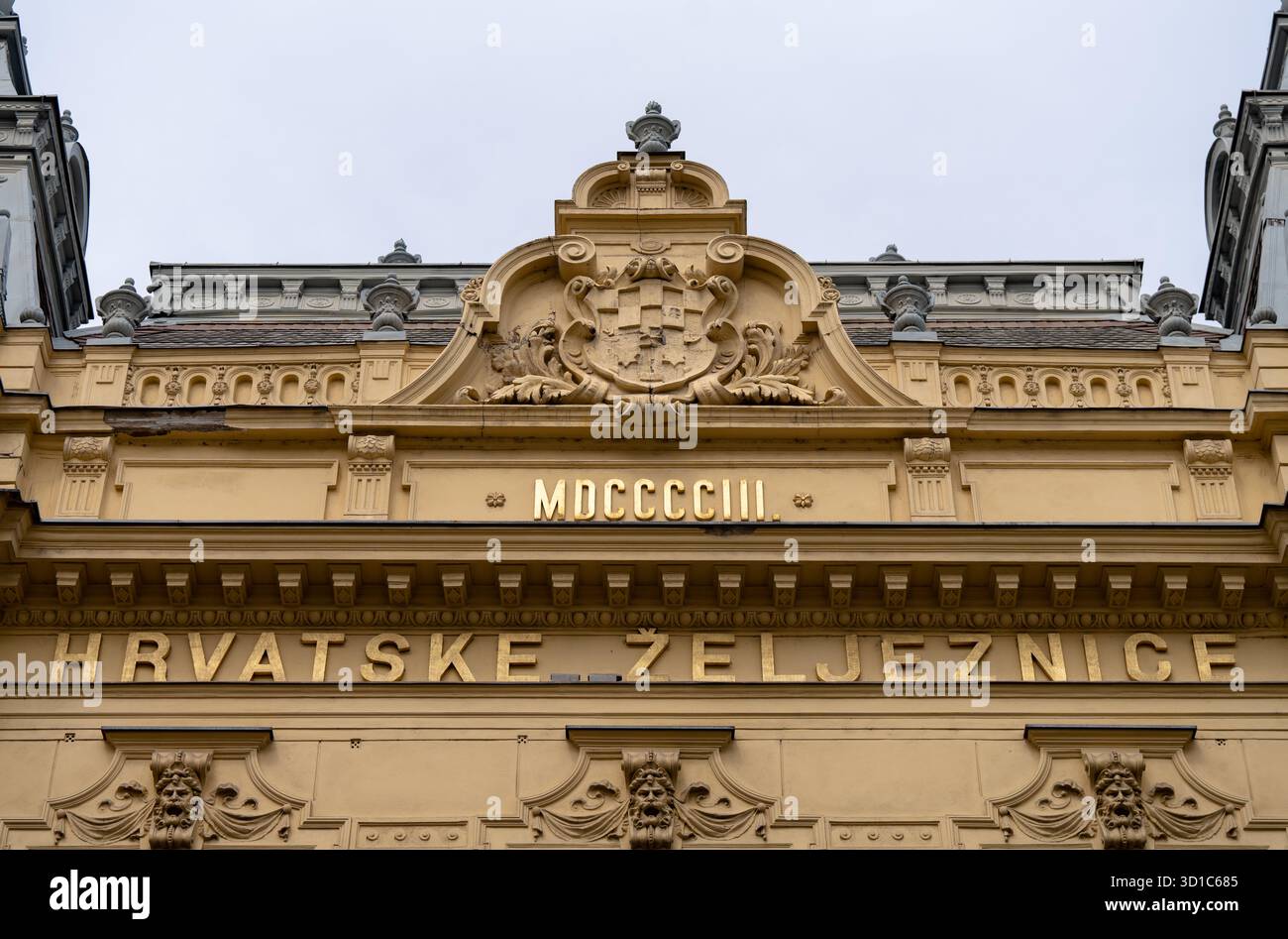 Zagabria, Croazia - 23 agosto 2024: Dettaglio facciata dell'ufficio della stazione ferroviaria di Zagabria con iscrizione dorata "Hrvatske Željeznice" e numeri romani MDC Foto Stock