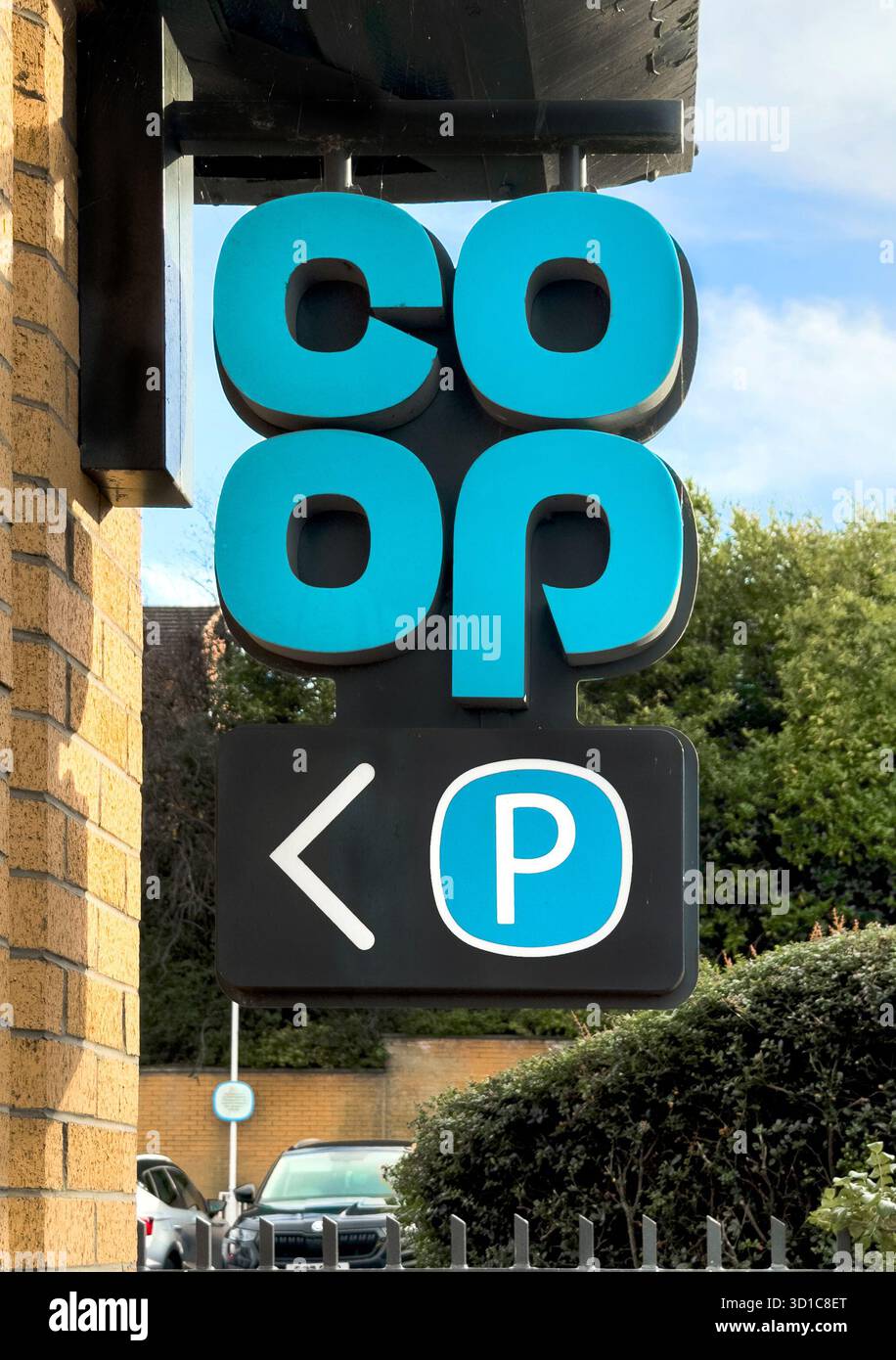 Cartello verticale per il supermercato Co-op con direzione di parcheggio montata su una parete di mattoni di fronte al verde e al cielo limpido Prudhoe northumberland Foto Stock
