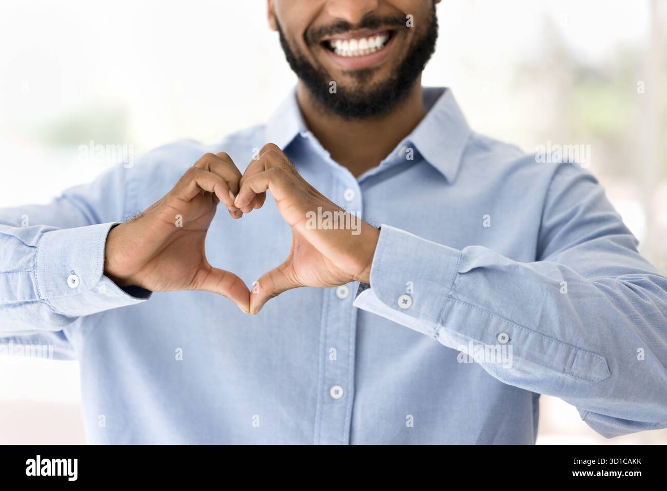 Uomo africano che forma la forma del cuore con le mani Foto Stock