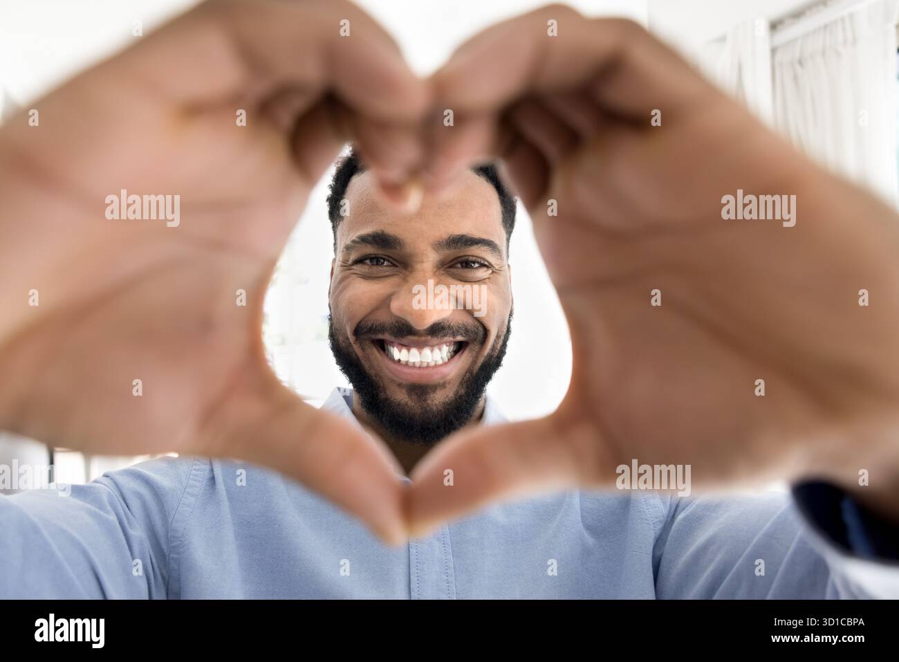 Uomo africano che si unisce alle dita mostrando il simbolo del cuore alla macchina fotografica Foto Stock