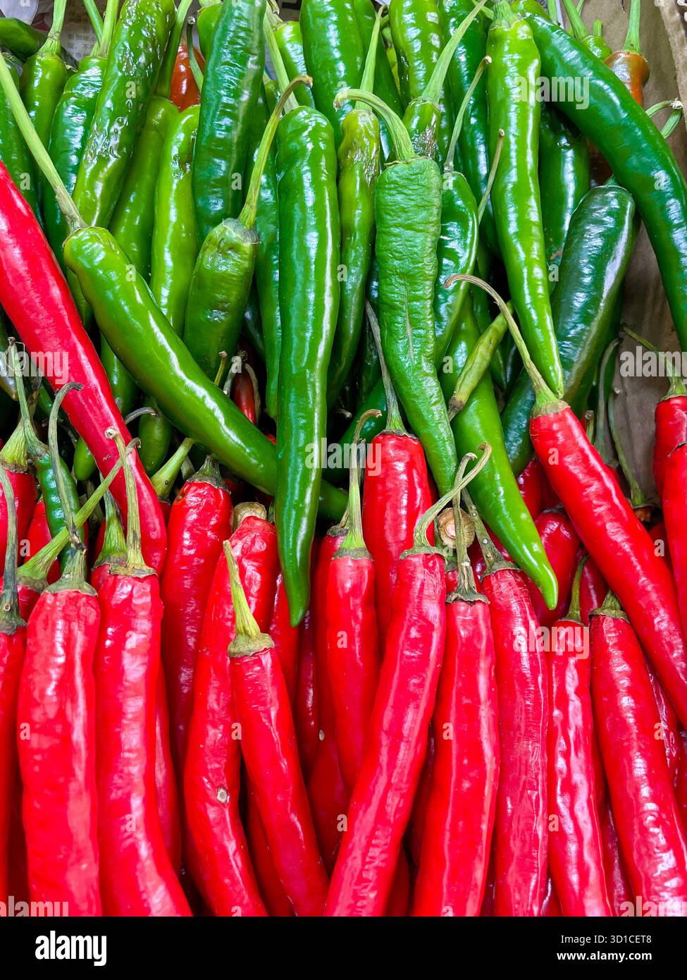 Vista ravvicinata dall'alto dei peperoncini rossi e verdi freschi impilati in una banchina del mercato in un'esposizione colorata e vivace Foto Stock