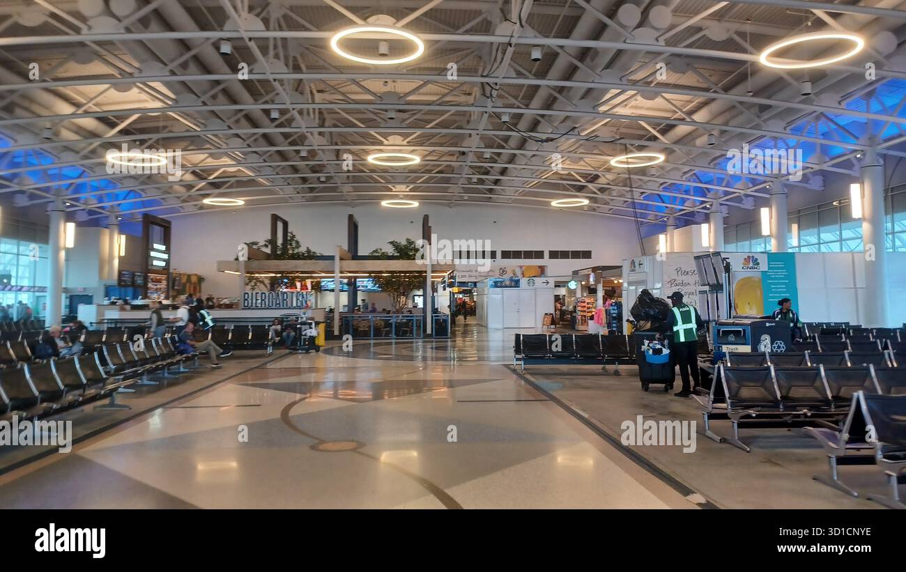 Charlotte, North Carolina, USA, 10 ottobre 2025: Le persone con bagagli attraversano un atrio luminoso e spazioso all'Aeroporto Internazionale Douglas di Charlotte. Foto Stock