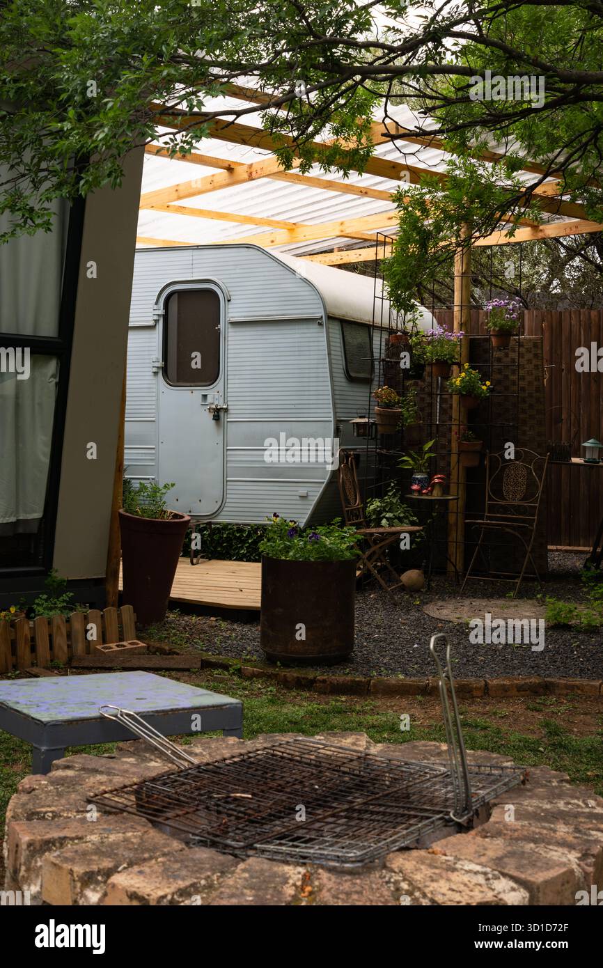 Caravan d'epoca in un accogliente giardino con caminetto all'aperto Foto Stock