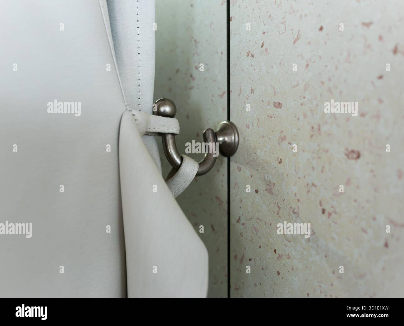 Gancio decorativo in metallo sulla parete per il fissaggio di tende pesanti. Foto Stock