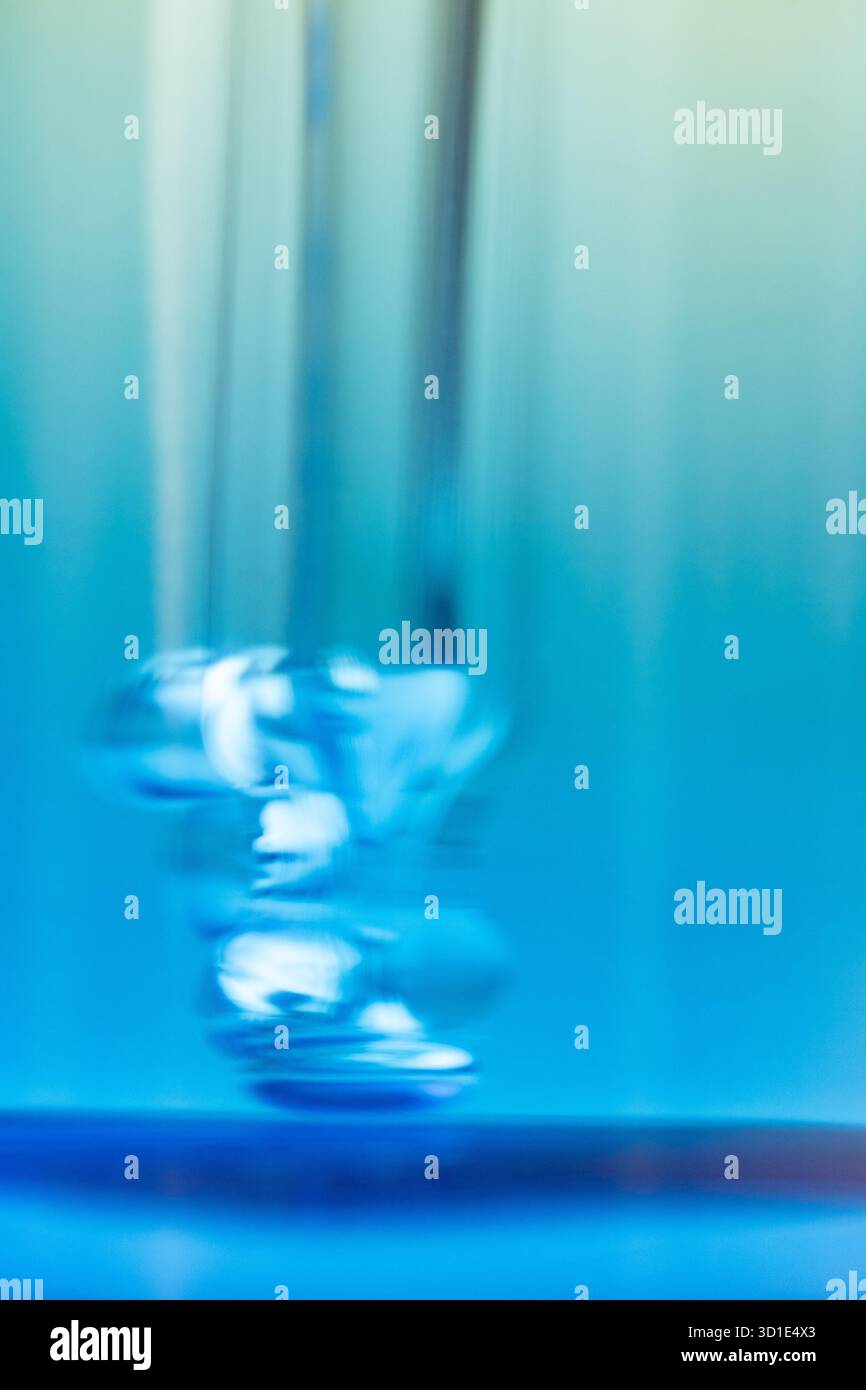 Foto ravvicinata di un contagocce con bolle d'aria all'interno di una bottiglia di vetro blu. Concetto di cosmetica, cura della pelle, siero, dettaglio del prodotto, consistenza, realismo Foto Stock