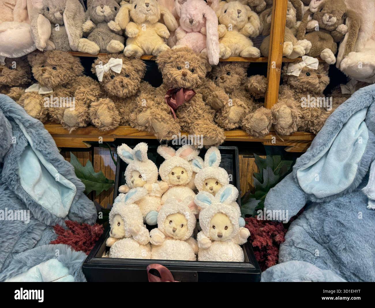Un'affascinante esposizione di vari orsetti peluche e bambole coniglietti impilati su scaffali in legno rustico, creando una scena stravagante e accogliente. Foto Stock
